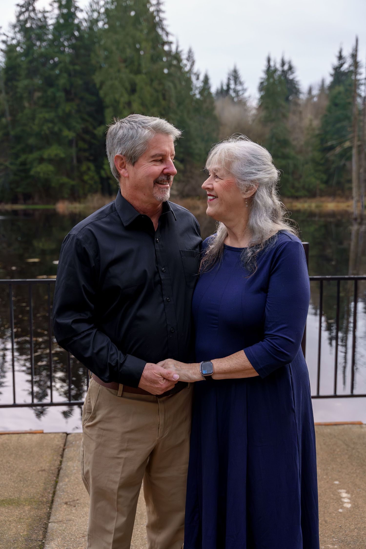 Couple in casual attire share tender moments outdoors against a winter forest backdrop.