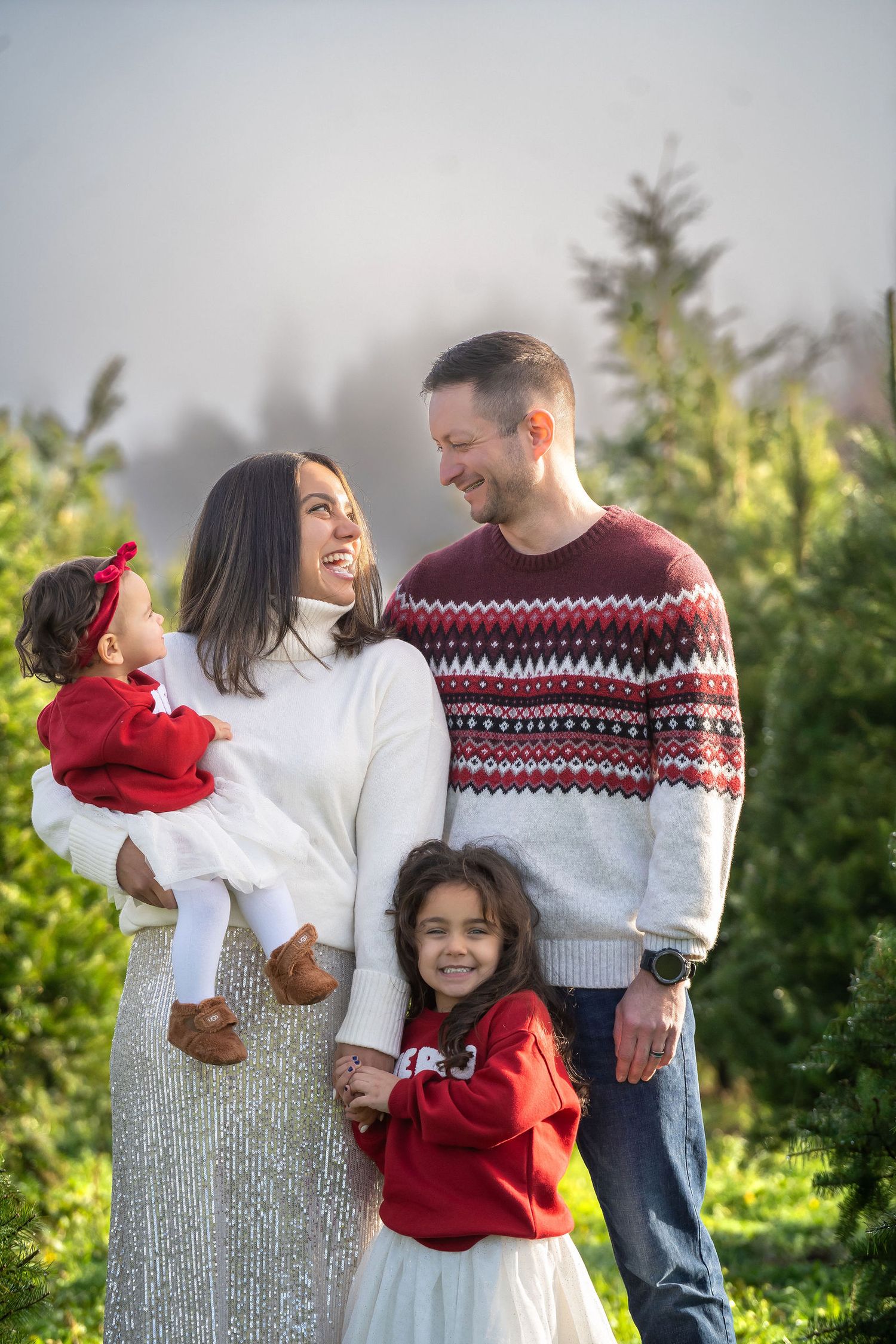 Family in winter sweaters sharing joyful moments together outdoors during a photo session in natural light.