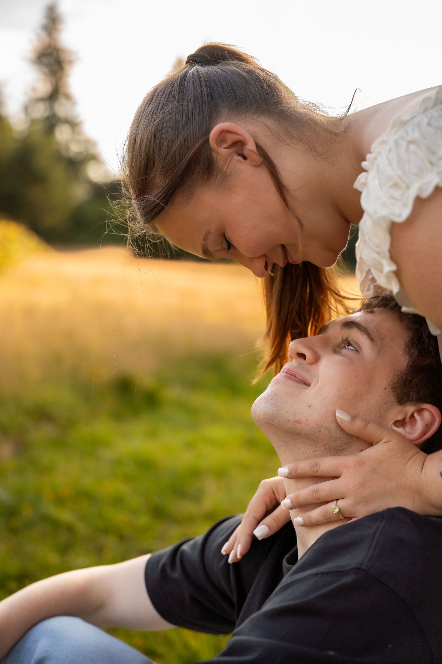 Romantic couple sharing an intimate moment in a golden sunlit field at sunset.