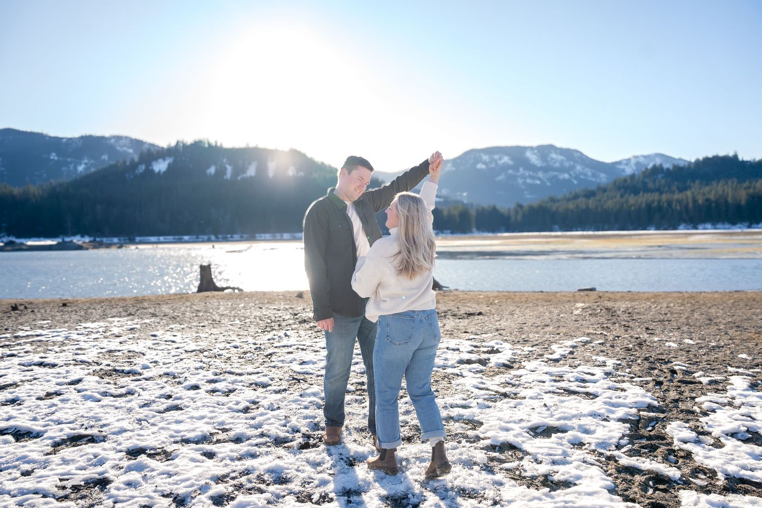 Couple dancing together on snowy ground with mountain landscape in background.