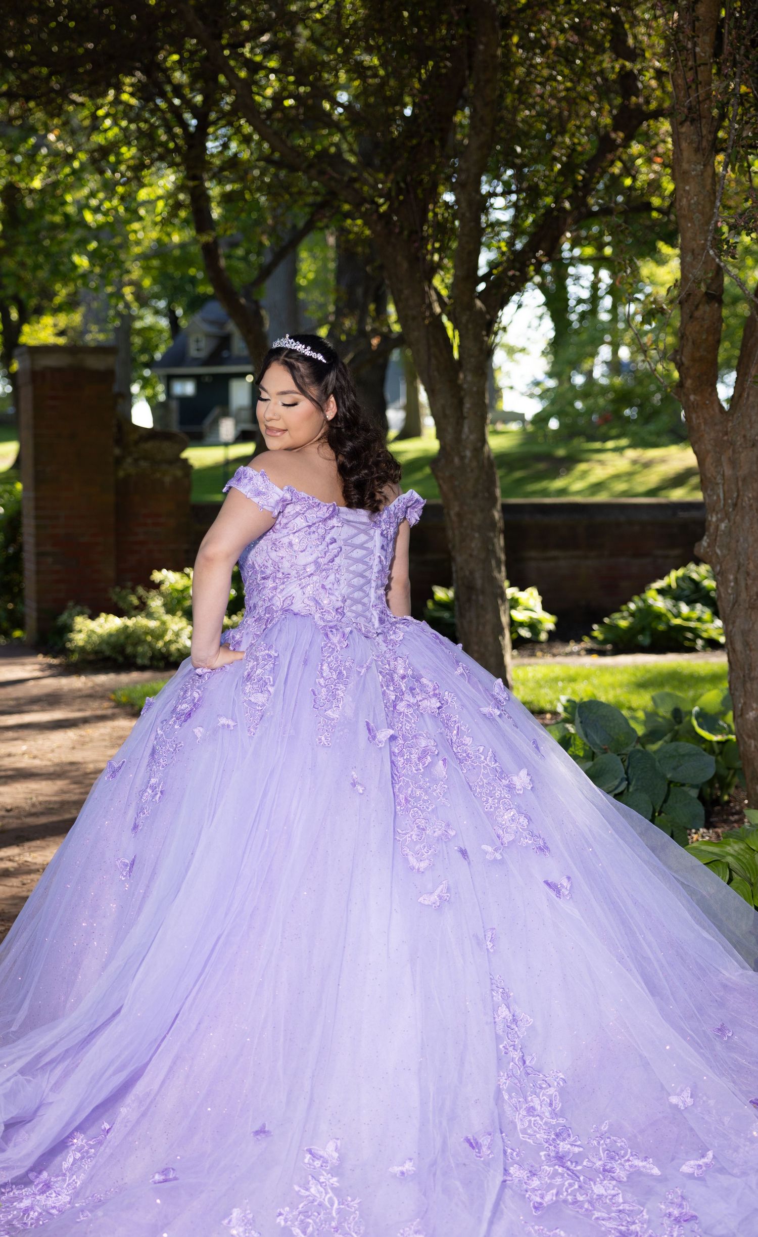 A stunning lavender ball gown with floral appliques and tulle skirt photographed in a garden setting.