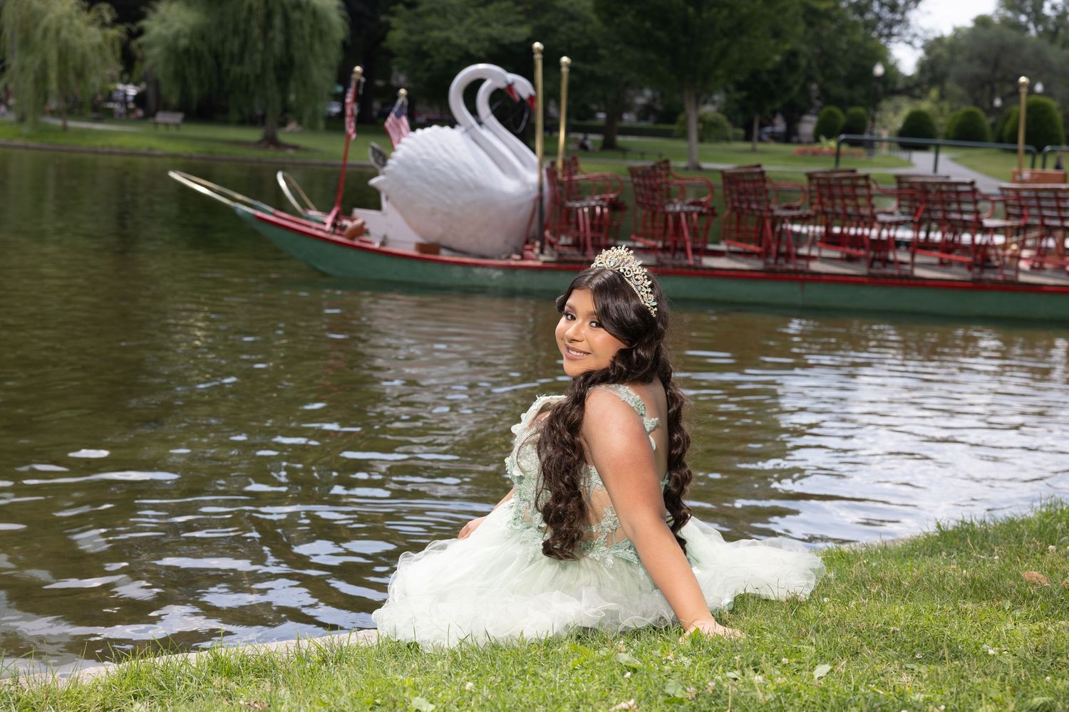 A person enjoys a peaceful summer day by a lake with boats and trees in the background.