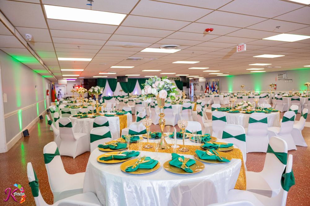 Banquet hall decorated in white and teal colors with round tables, chairs, and hanging paper lanterns for a special event.