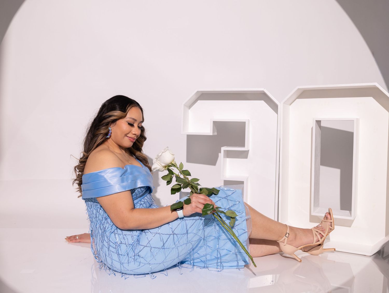 Woman in light blue off-shoulder dress poses with white letters and roses in a photo series.