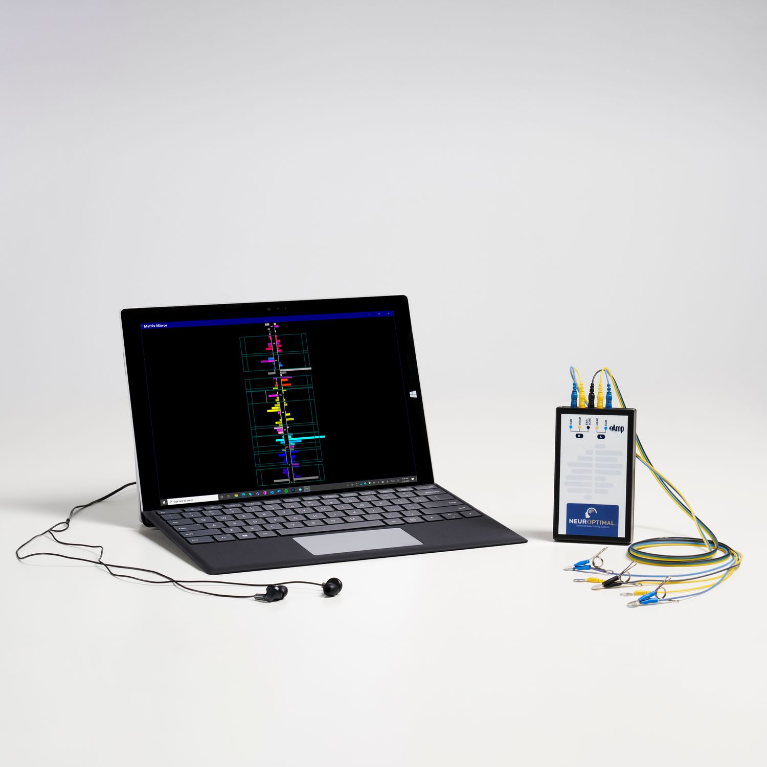 A laptop displays waveform data next to a small medical device with electrode cables connected for monitoring purposes.