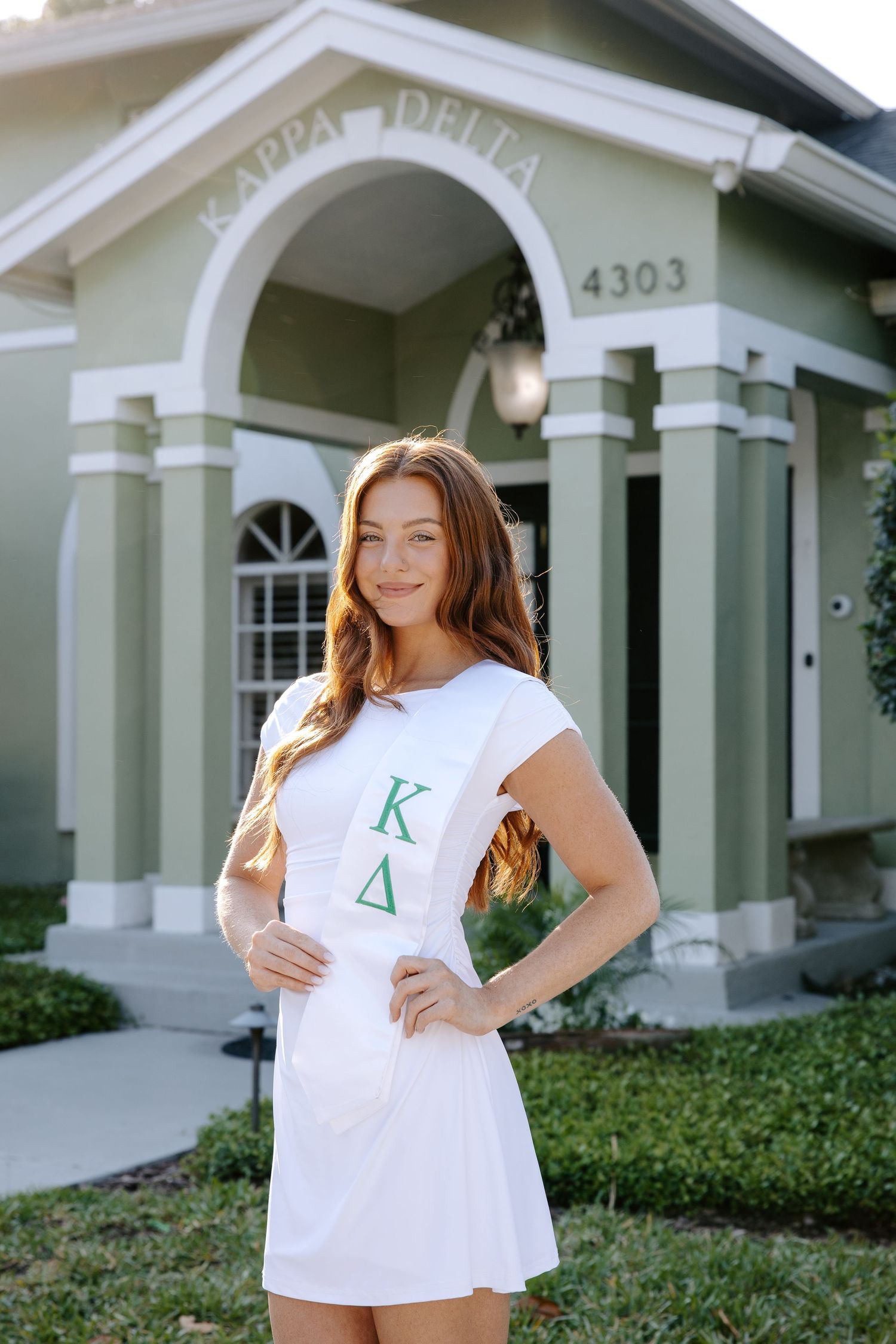 College sorority photos taken outside a white building with Greek letters.