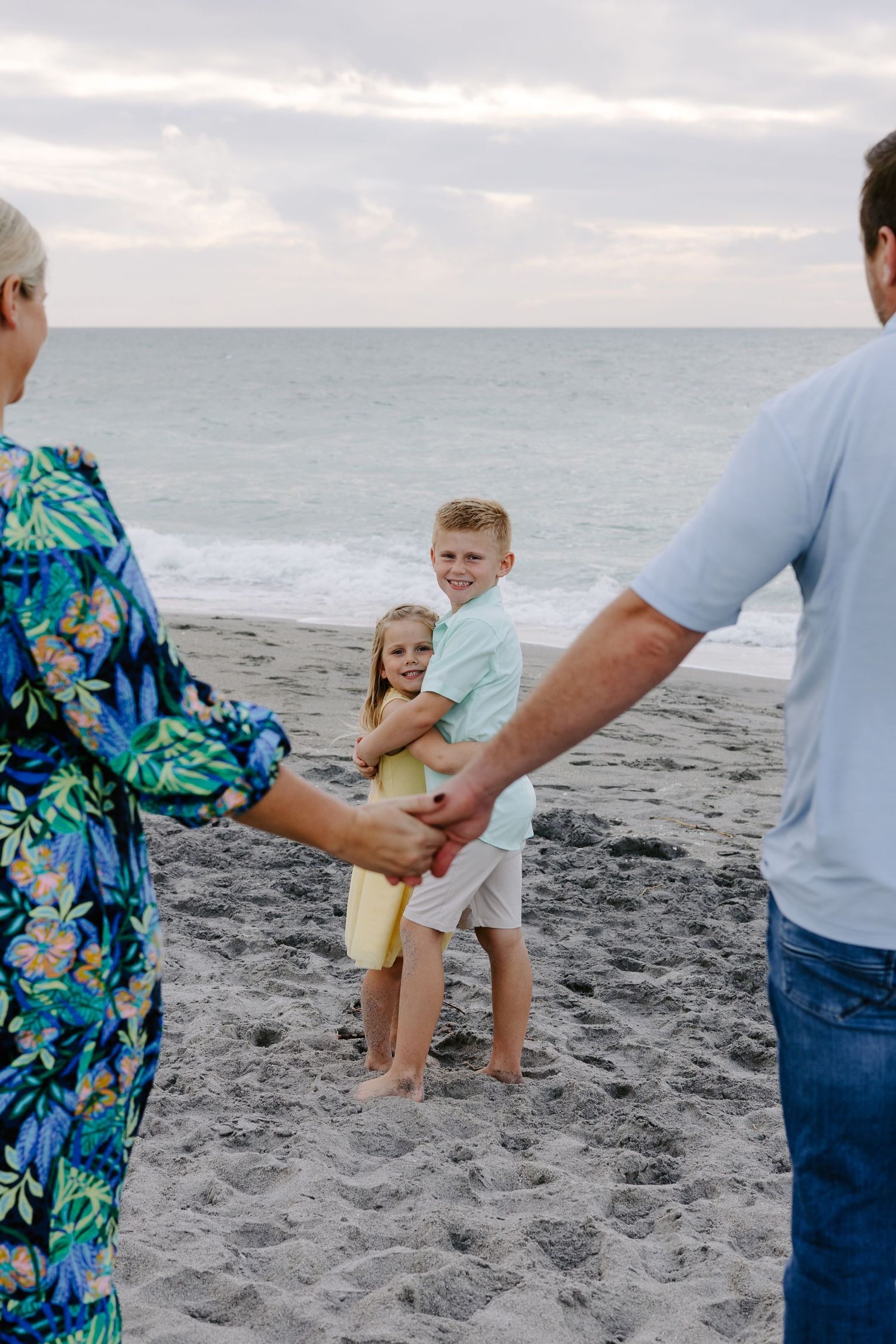 Series of playful beach moments with family members swinging child near ocean.
