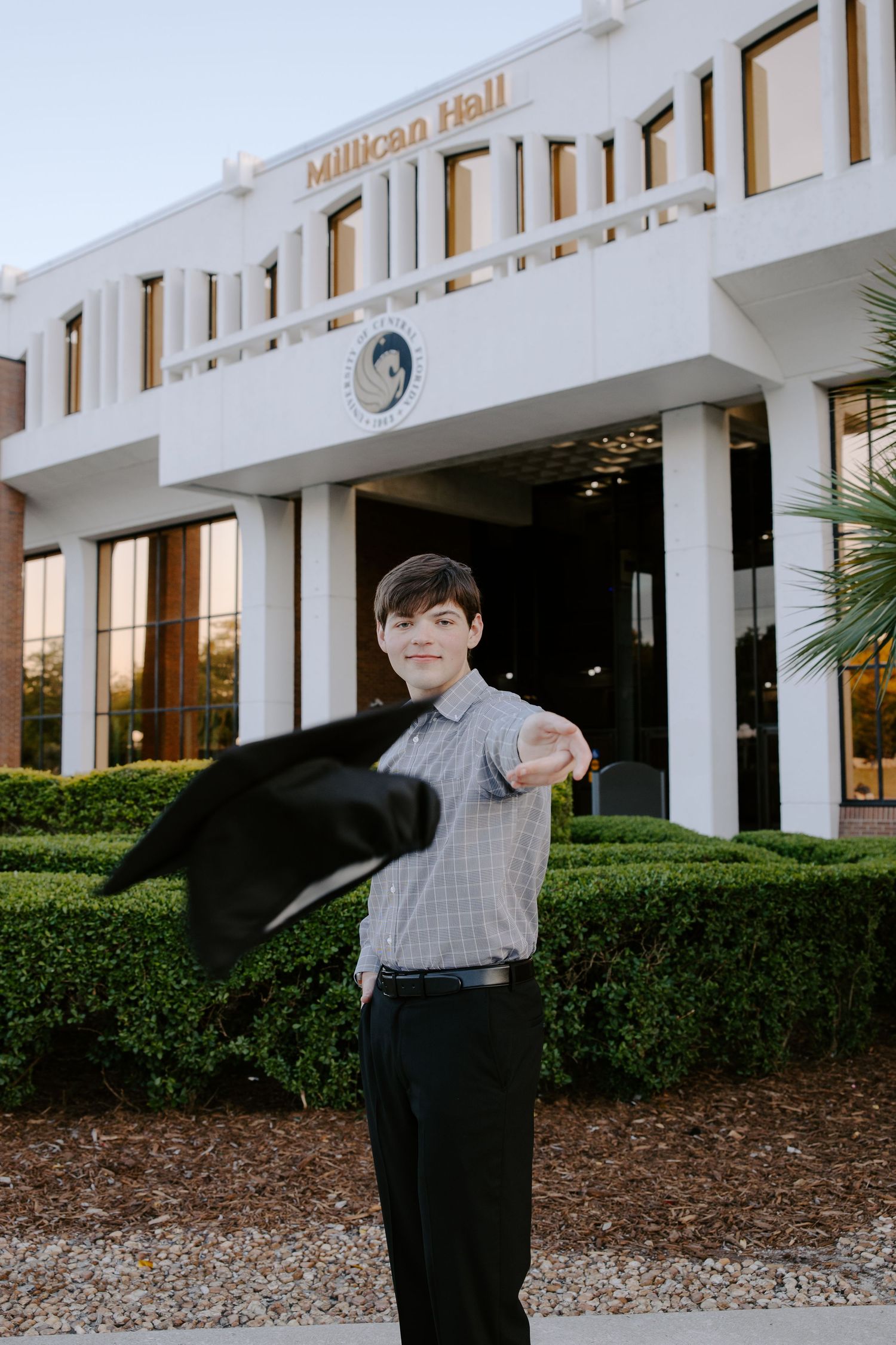 Graduate poses outside Millican Hall building during graduation photo session.
