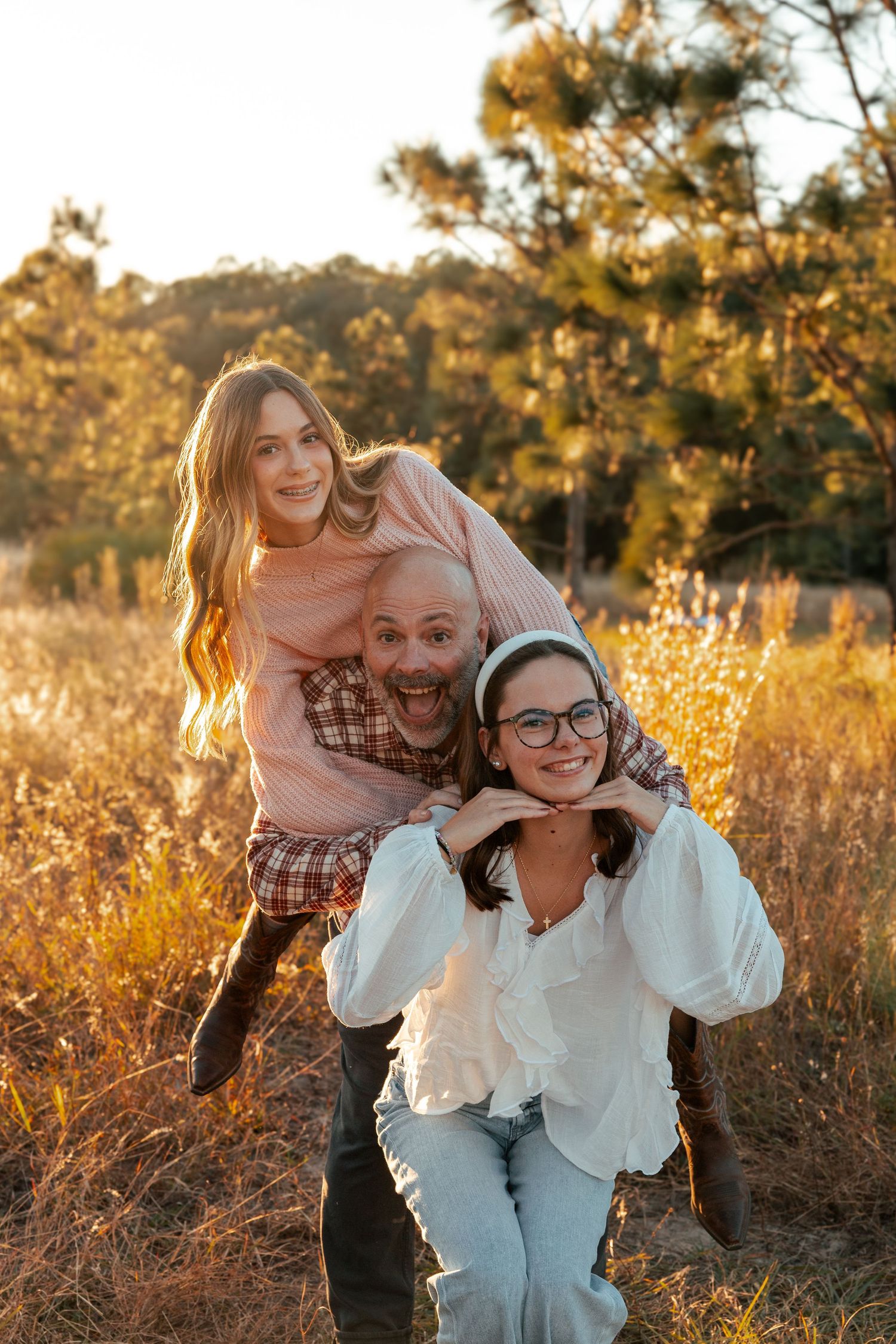 A playful outdoor photoshoot in a golden field during sunset with warm lighting and natural scenery.