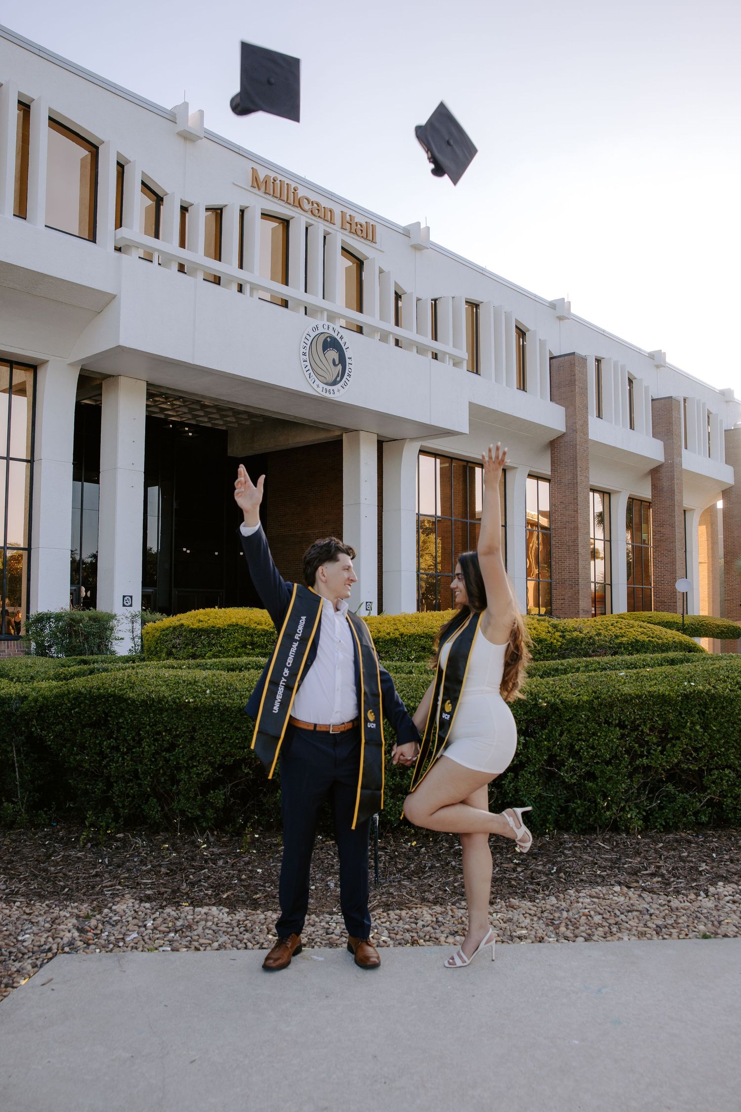 Graduates toss caps in front of university building during celebration.