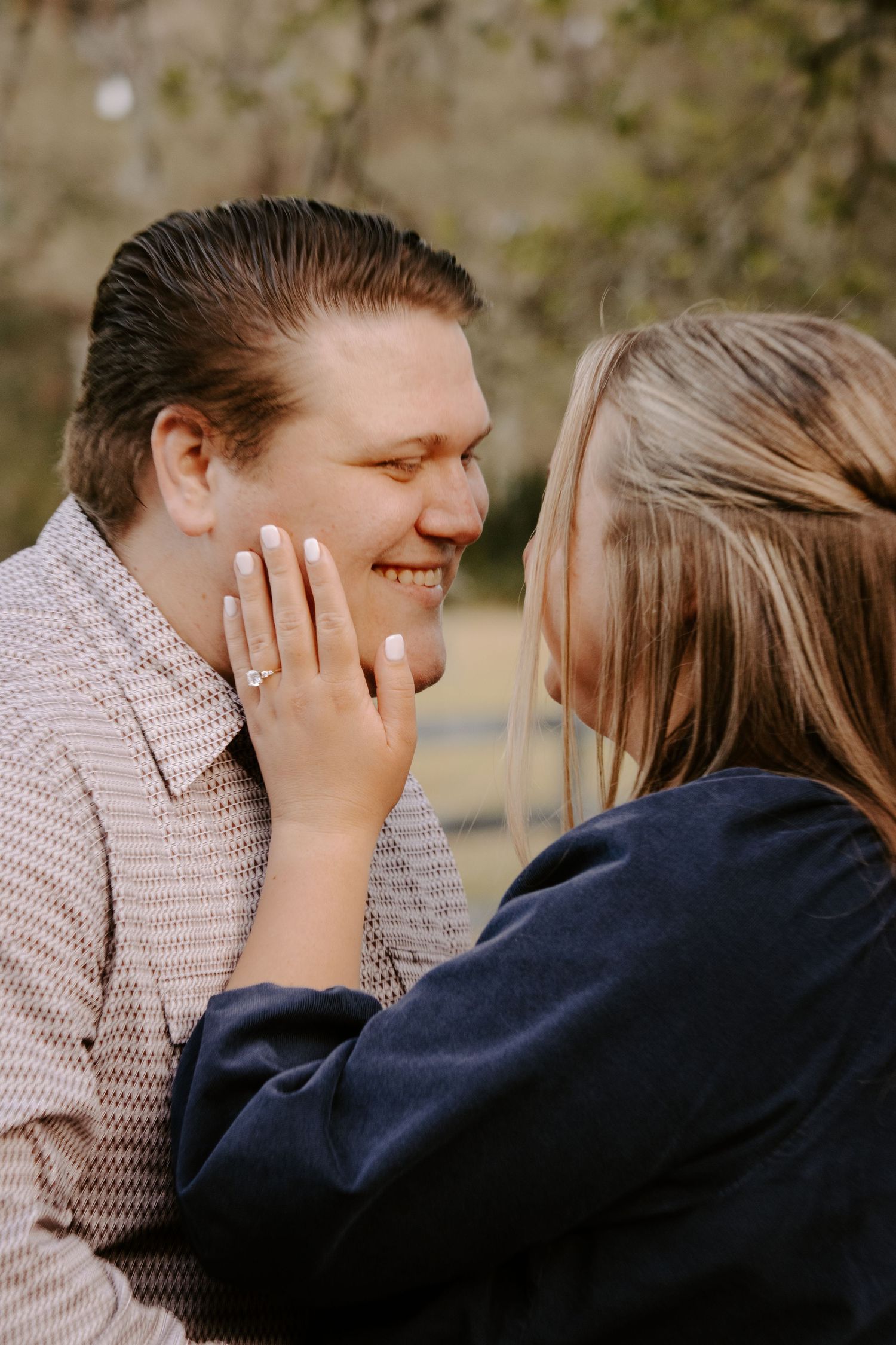 A couple shares a sweet candid moment laughing together during an outdoor photo session.