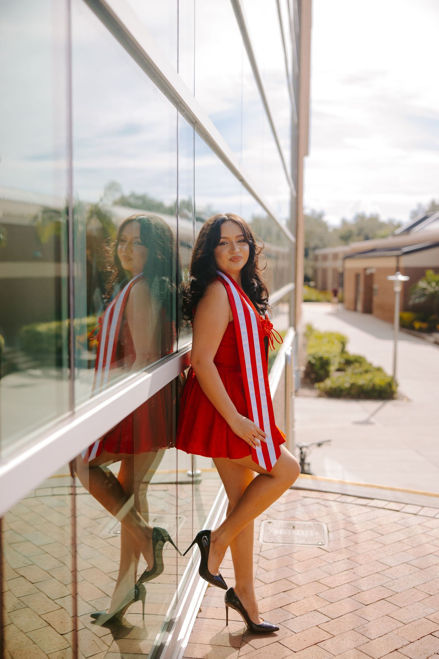 Series of photos showing student in red dress posing against reflective glass building.