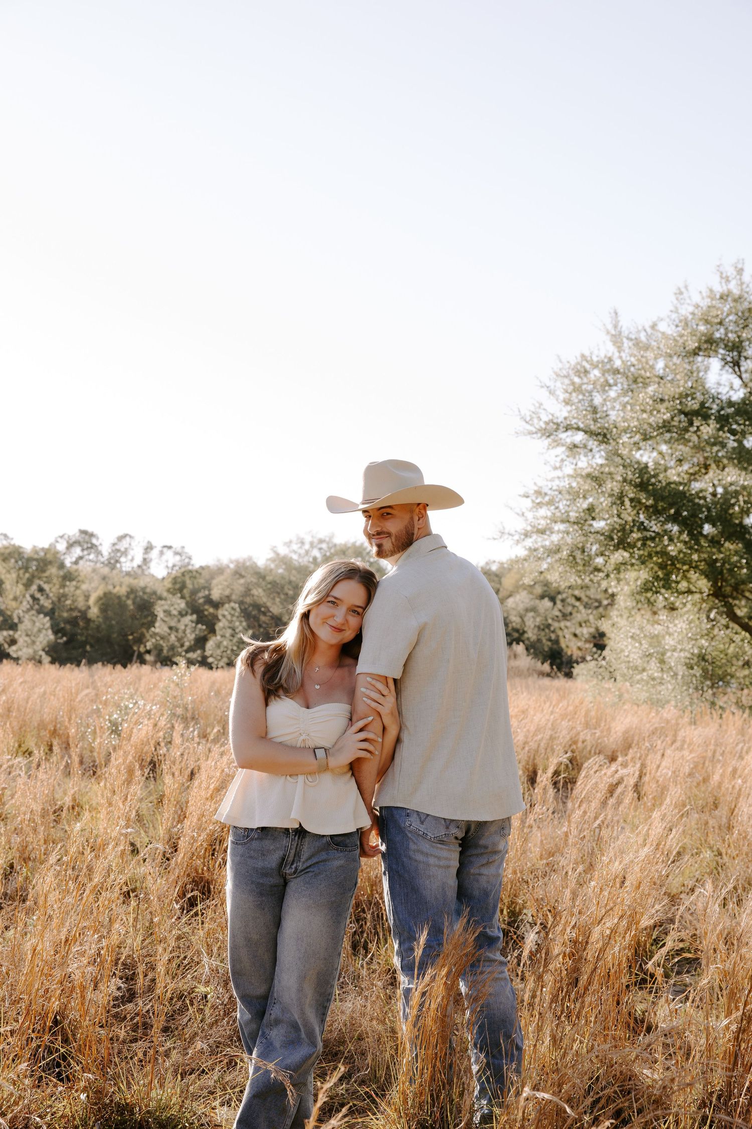 Couple shares tender moments in golden field during sunset photoshoot.