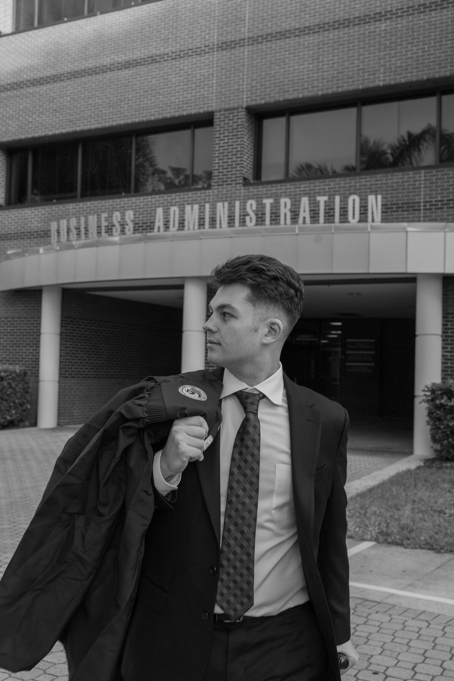 A series of four black and white photos showing a person in a suit and tie standing outside a business building.