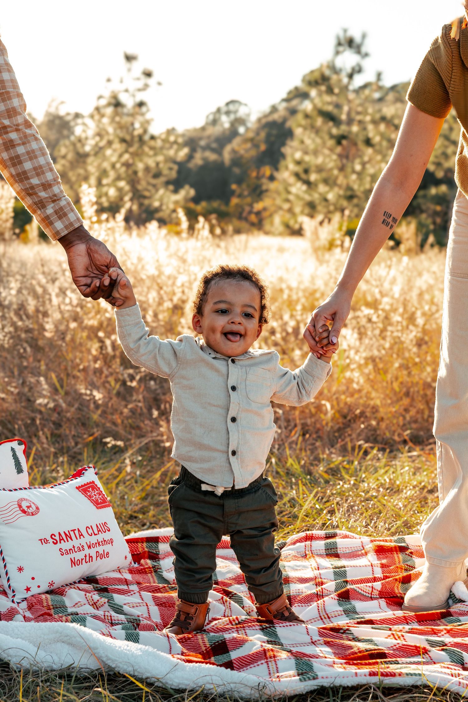 A toddler plays joyfully on a red and white checkered picnic blanket in a sun-drenched field during golden hour.