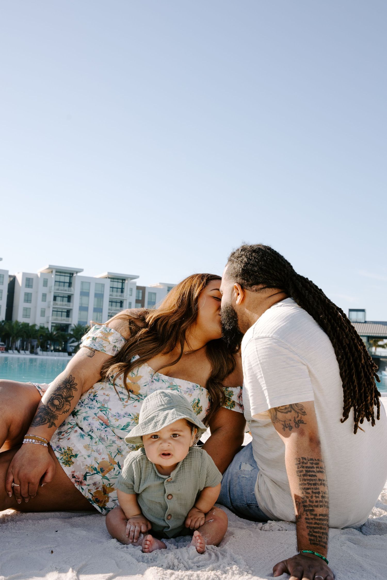 Sweet family moment shared on a sunny beach with palm trees and blue water.
