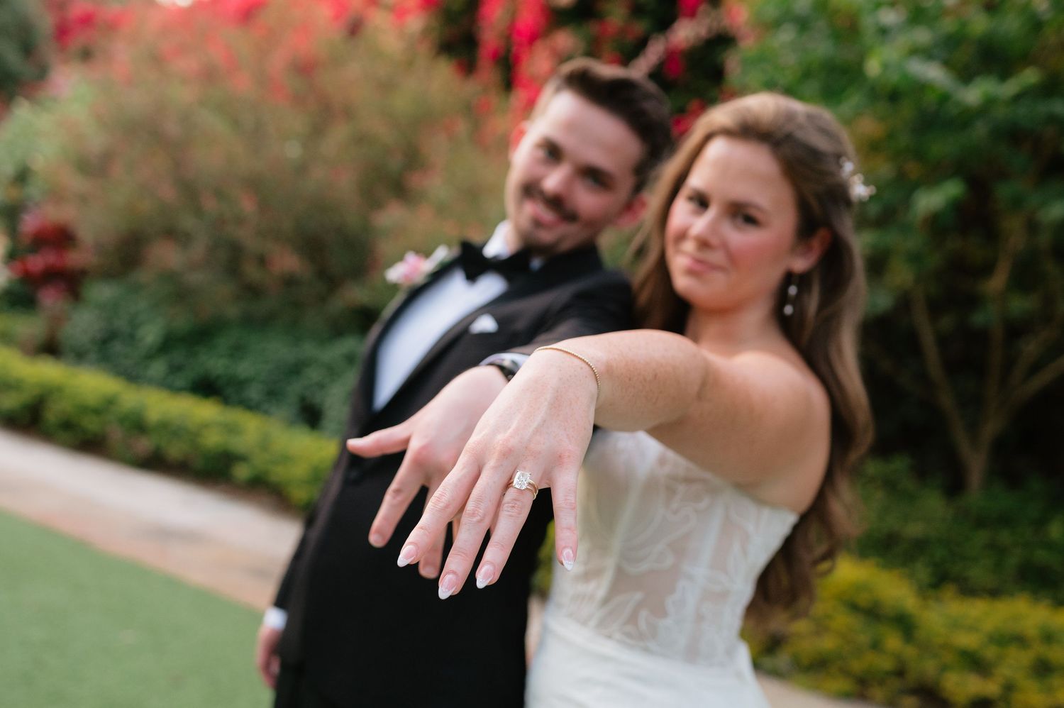 Wedding couple shares a romantic moment in a garden with autumn foliage in the background.