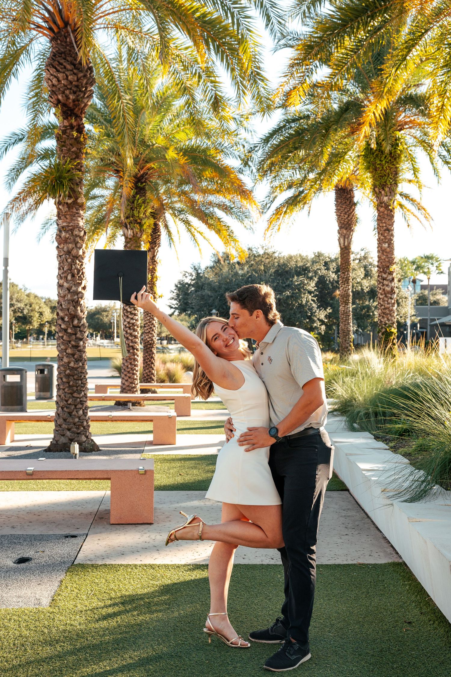 A couple dances together on a palm tree-lined path during a romantic outdoor photoshoot at sunset.