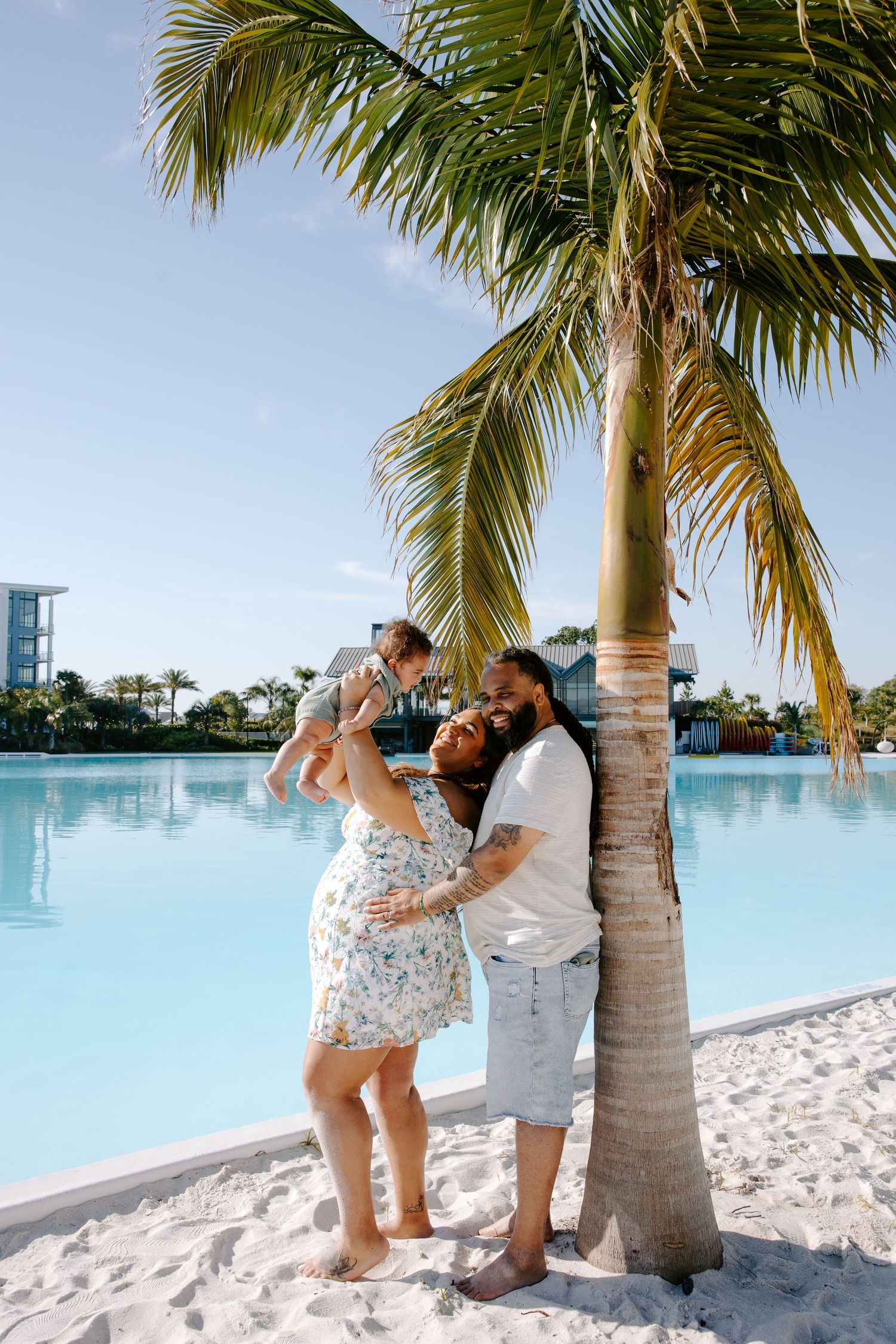 A couple shares a romantic moment near a palm tree on a tropical beach.