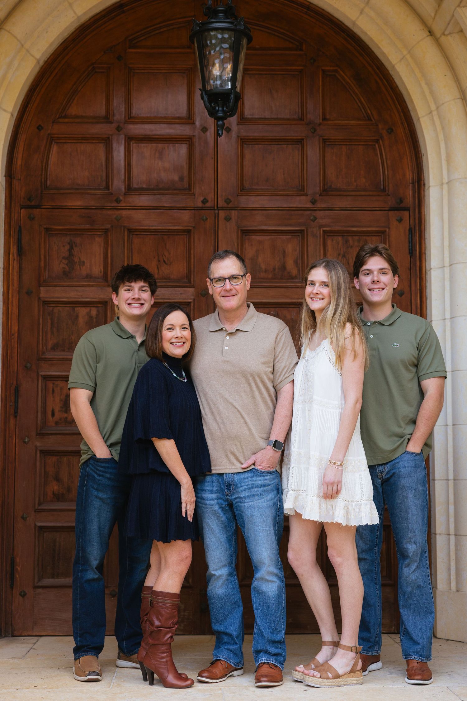 Family portrait session showing legs and feet arranged in front of ornate wooden doors at a historic building.