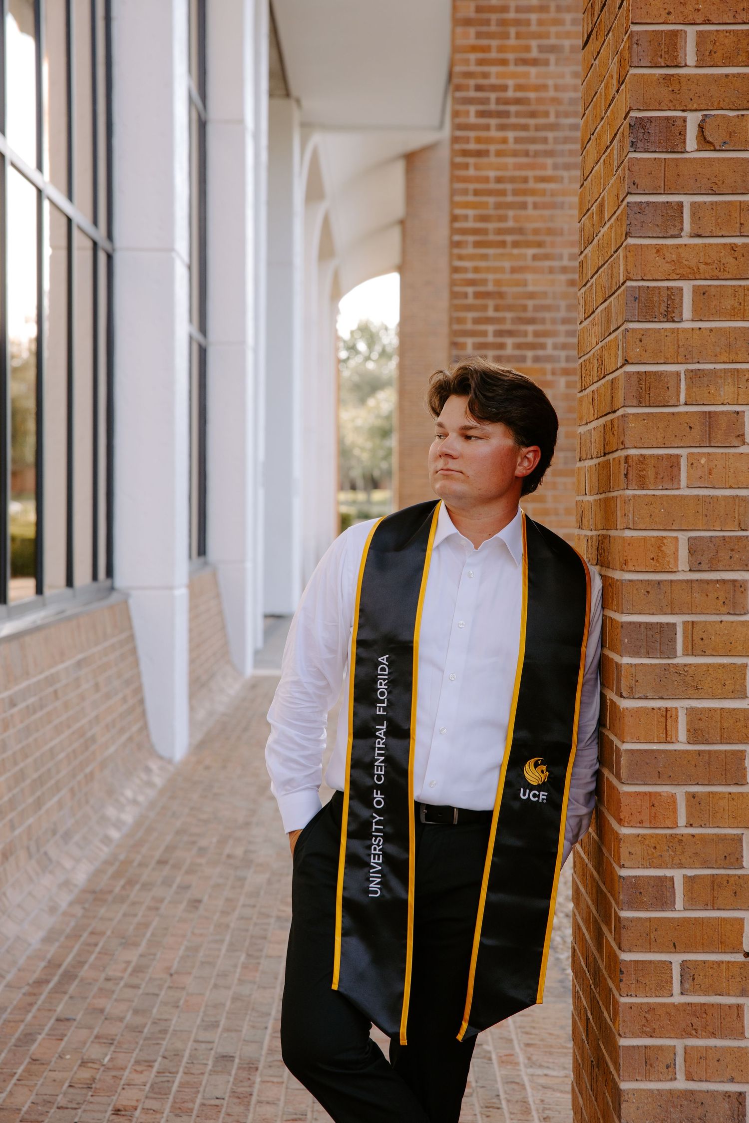 Artistic graduation portraits taken in brick hallway with academic stole.