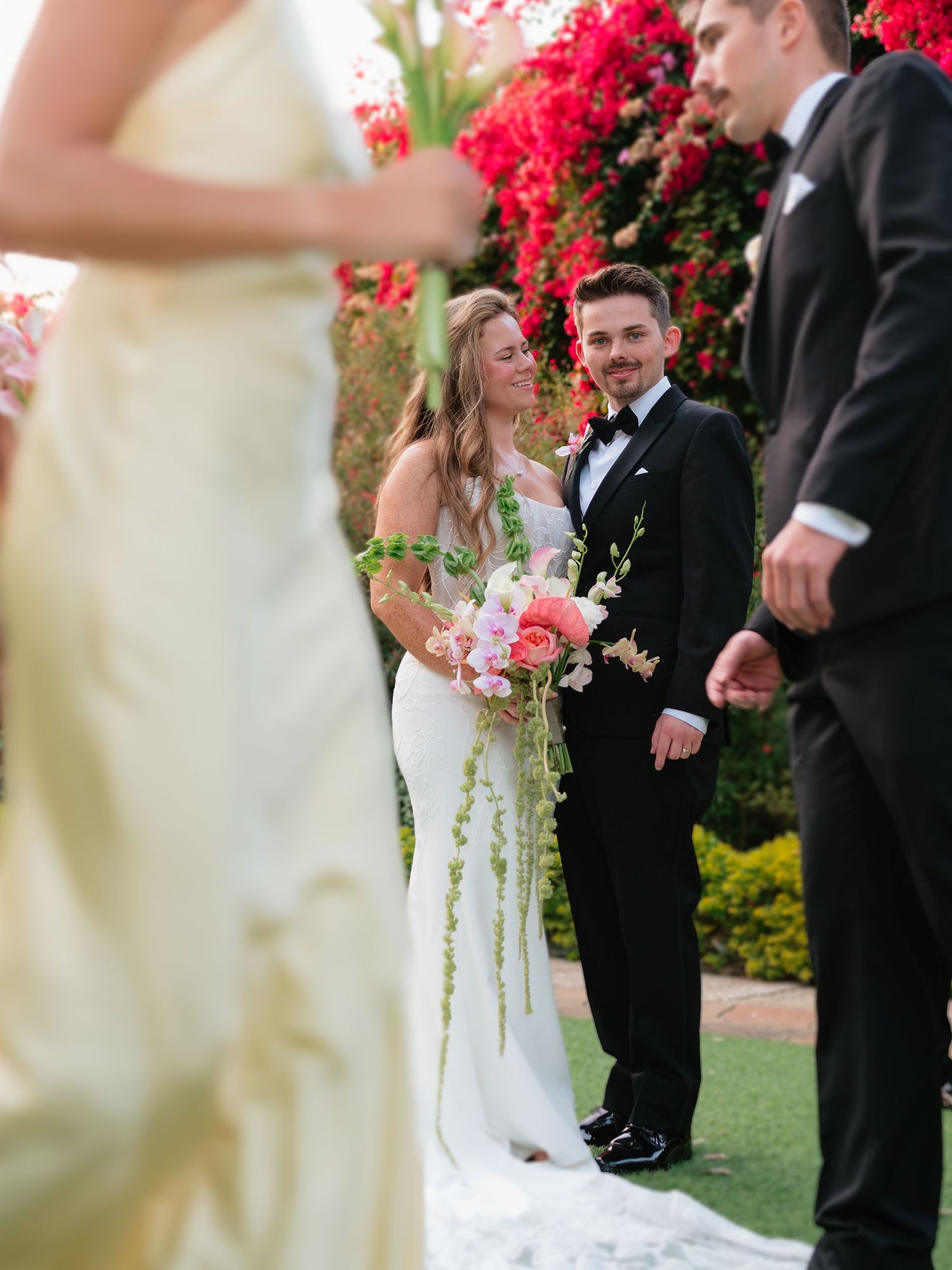 Wedding ceremony setup with bright red floral arrangements and white decor outdoors.