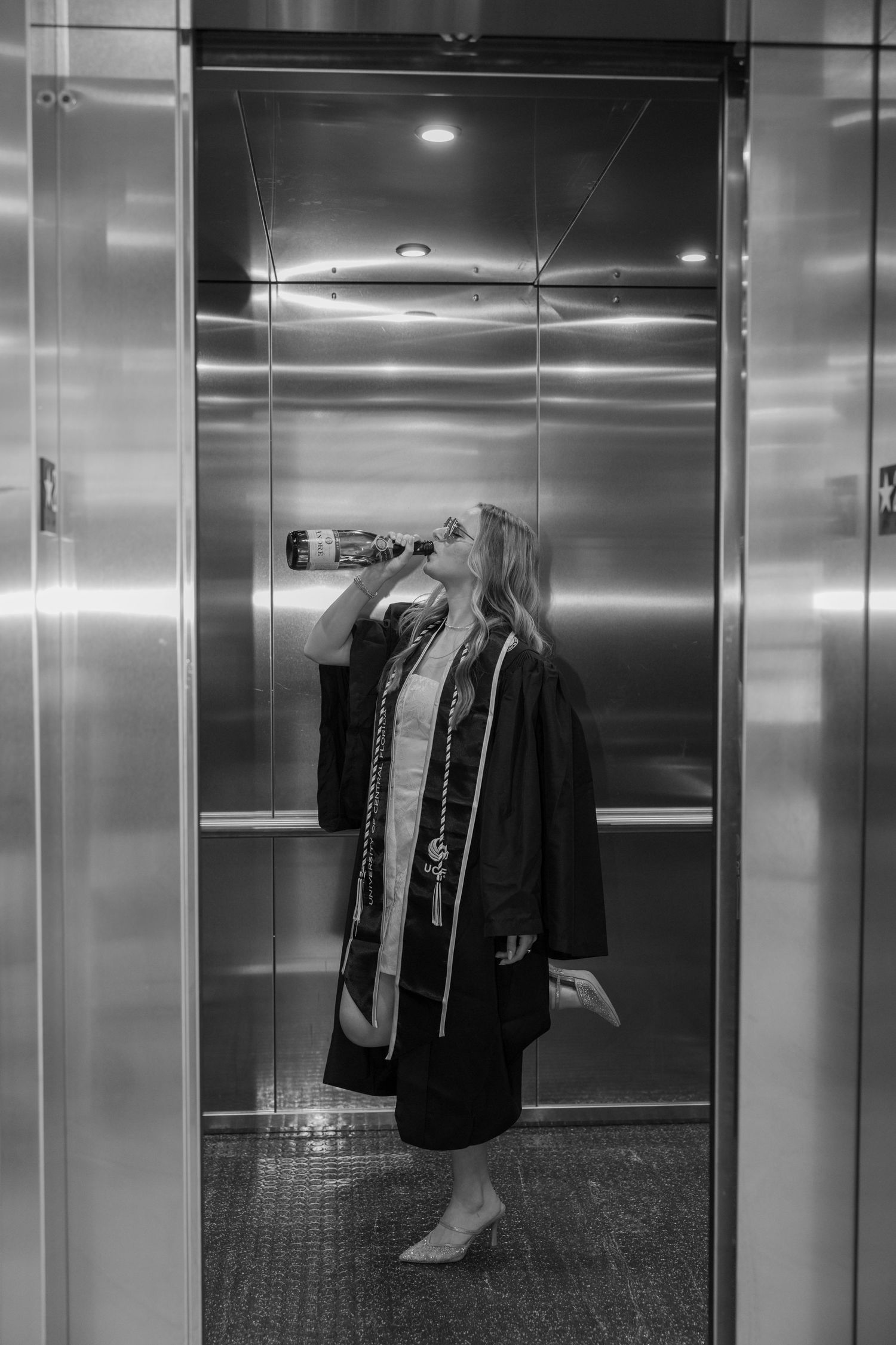 Empty elevator interior with clothing items hanging on the walls in a monochromatic setting.