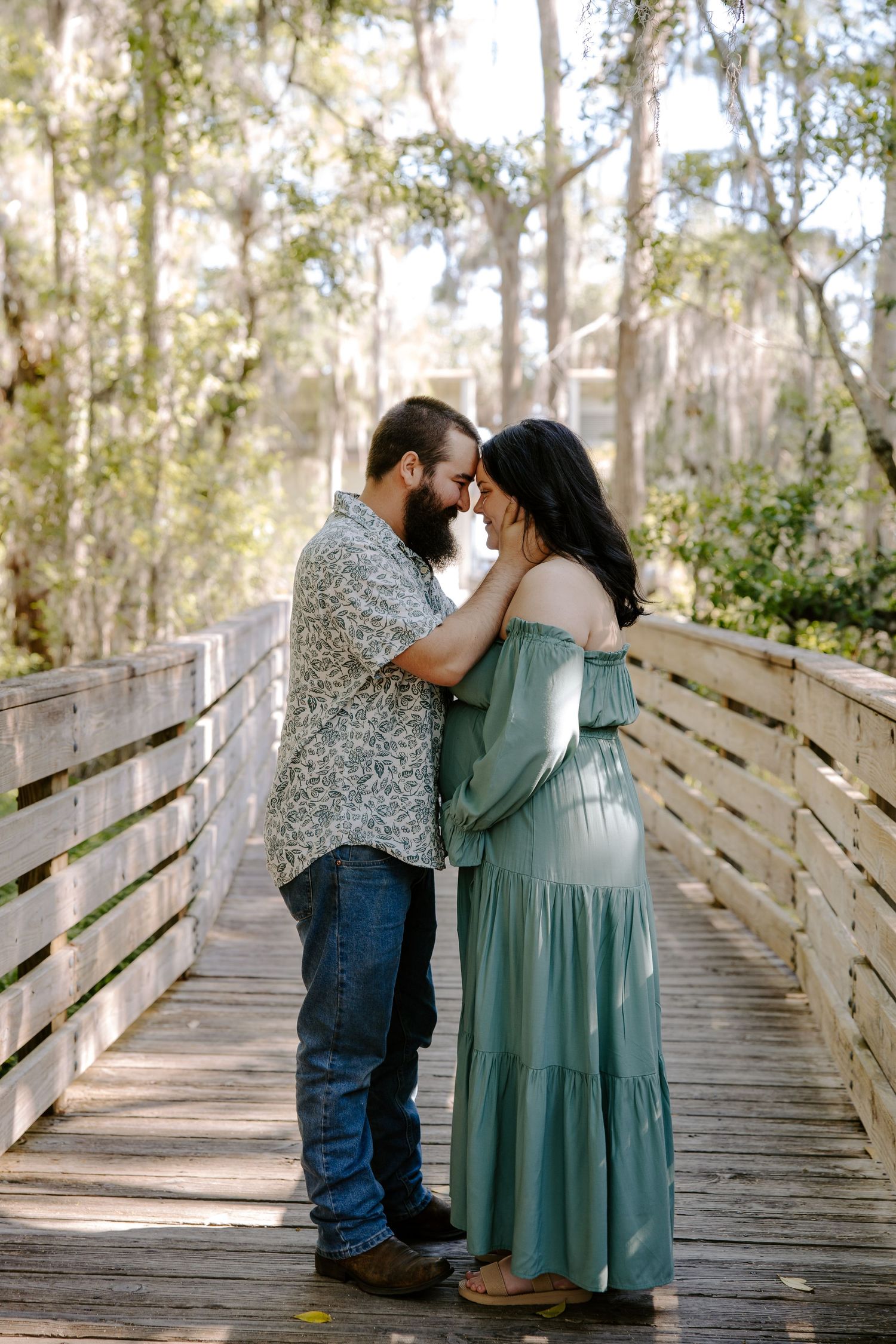 Romantic moment captured on wooden boardwalk surrounded by Spanish moss trees.