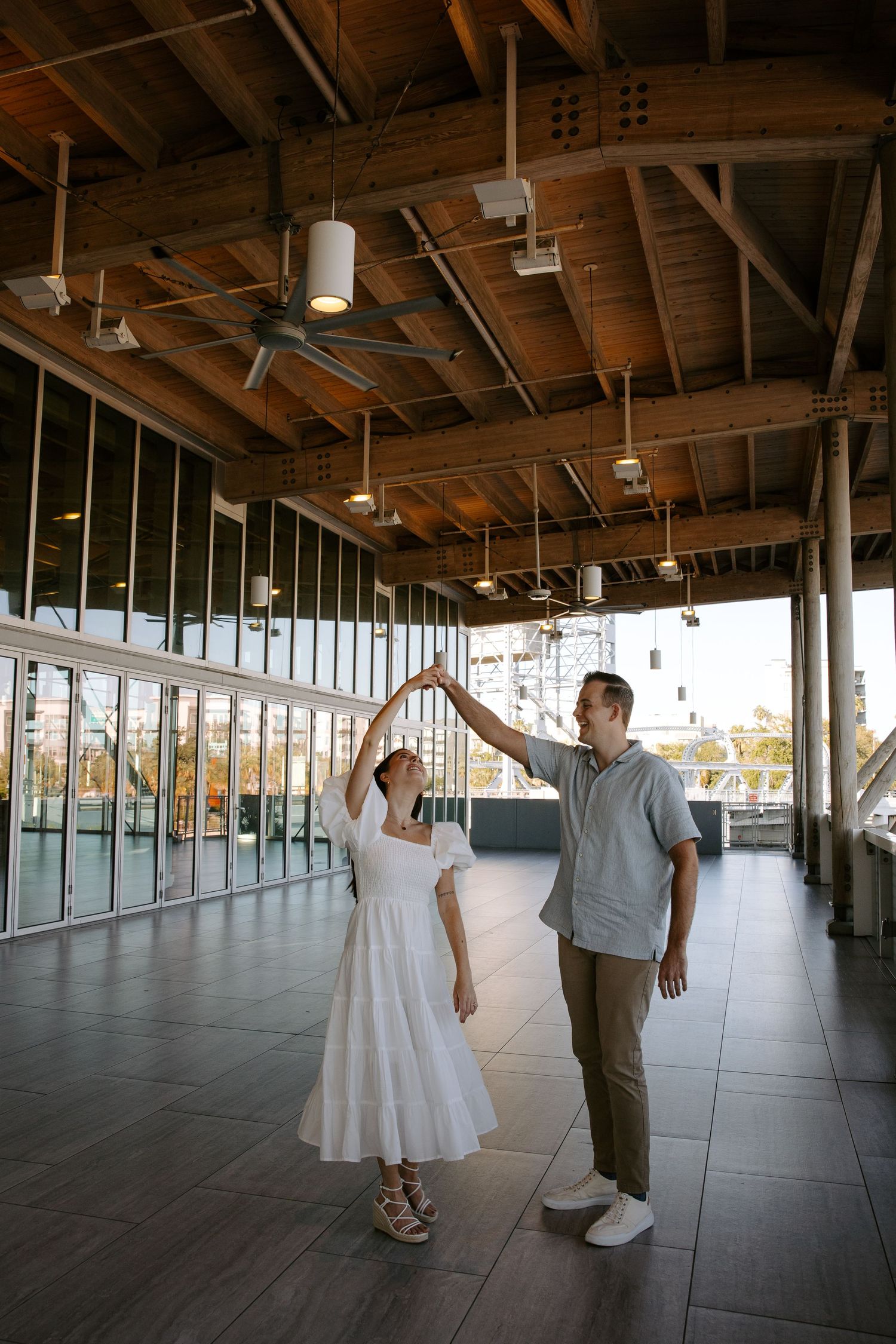 Couple dancing together in an empty industrial space with wooden ceiling.