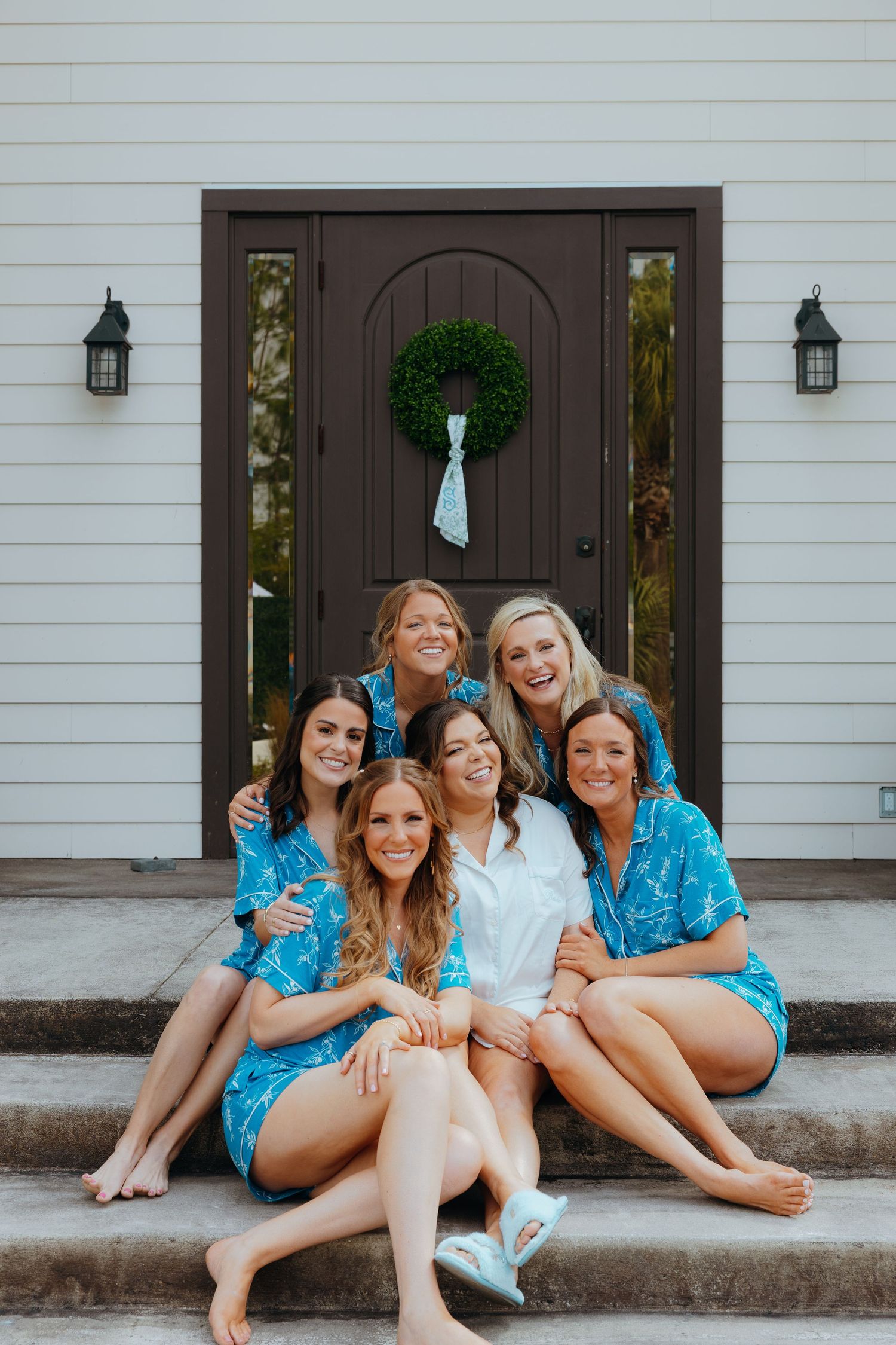 Friends in matching blue outfits sitting together on white building steps.