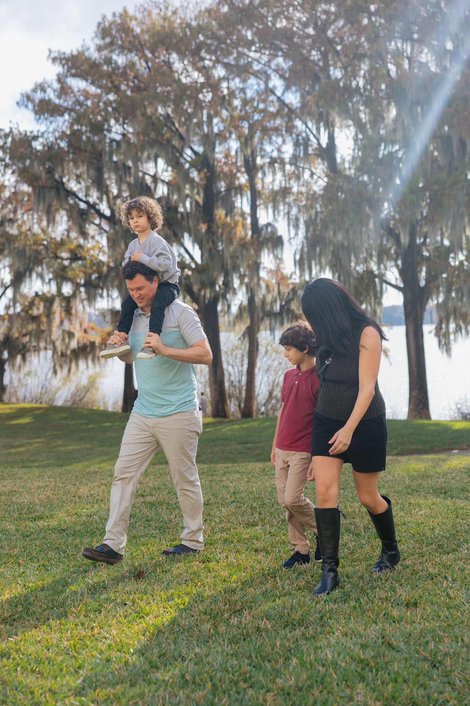 A group practices self-defense moves on a grassy hillside with Spanish moss-draped trees in the background.