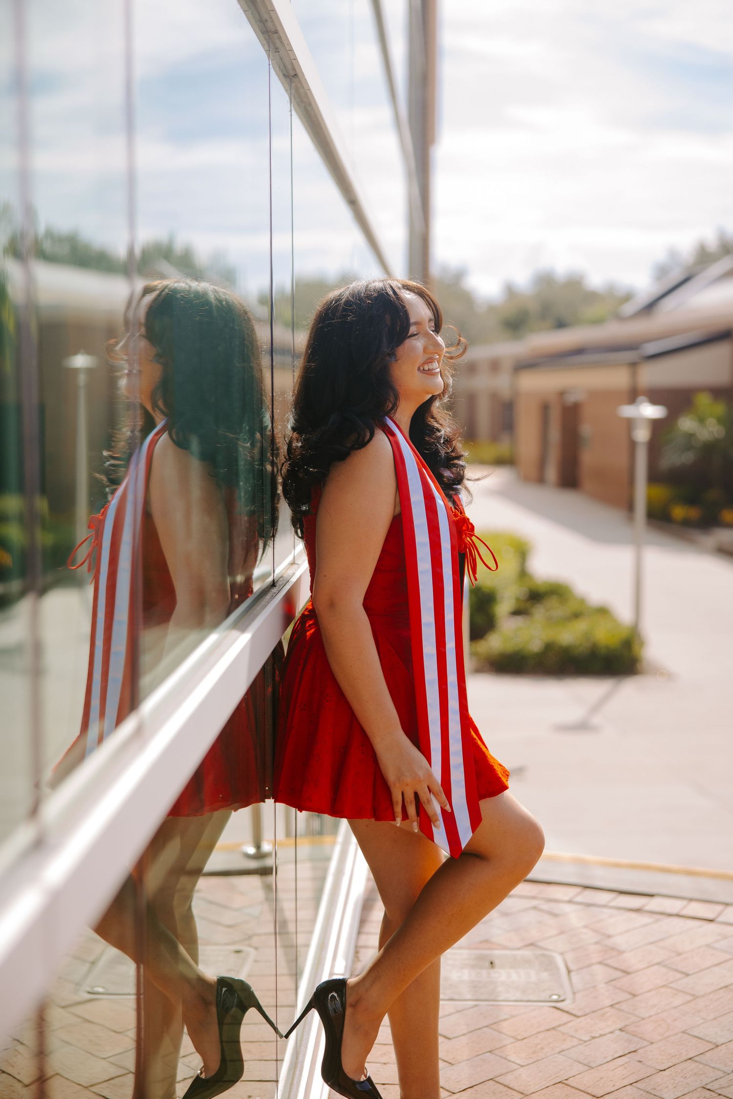 Series of playful poses against a glass window in a red and white striped outfit.