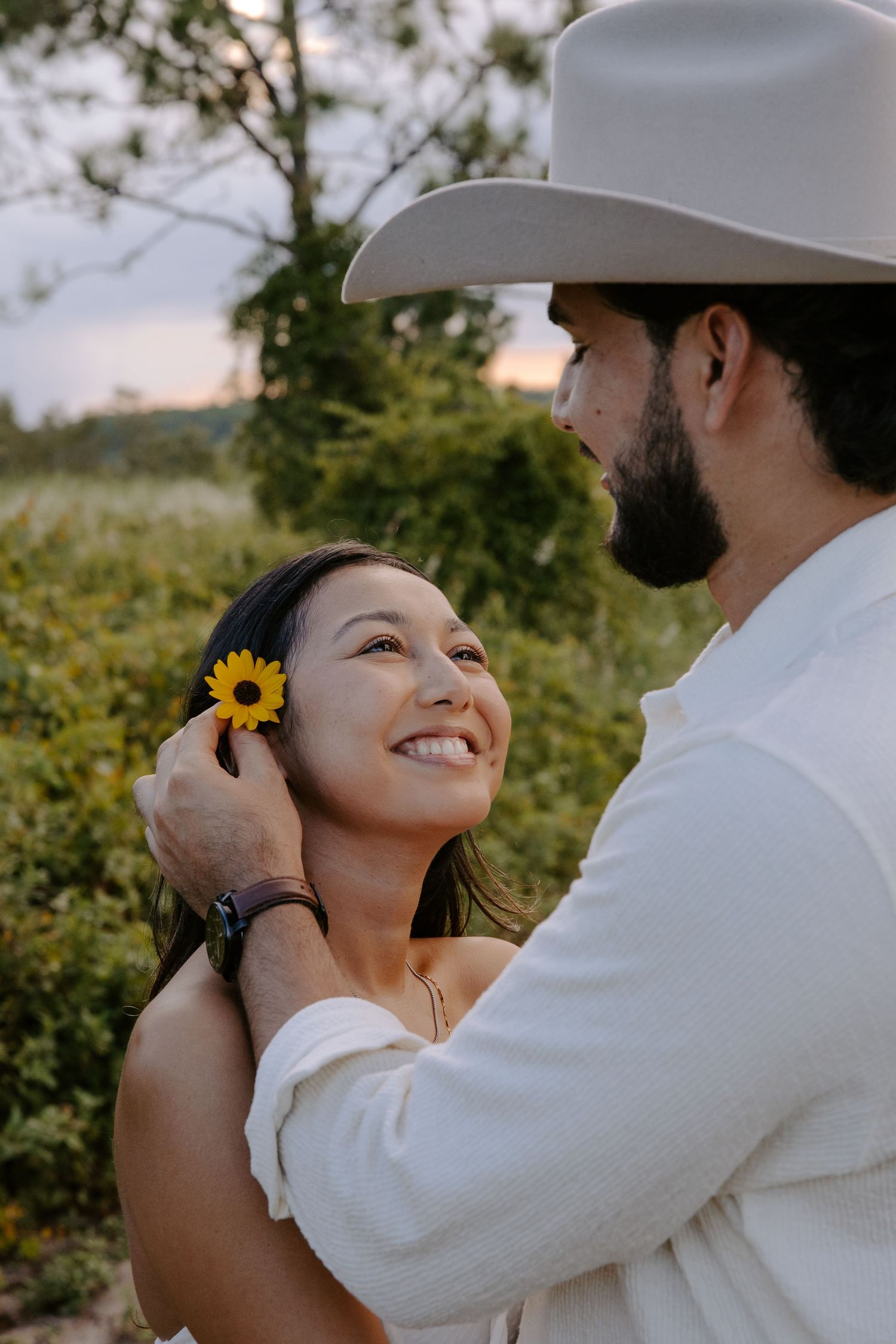 Romantic couple portraits in a field with sunflowers at sunset.