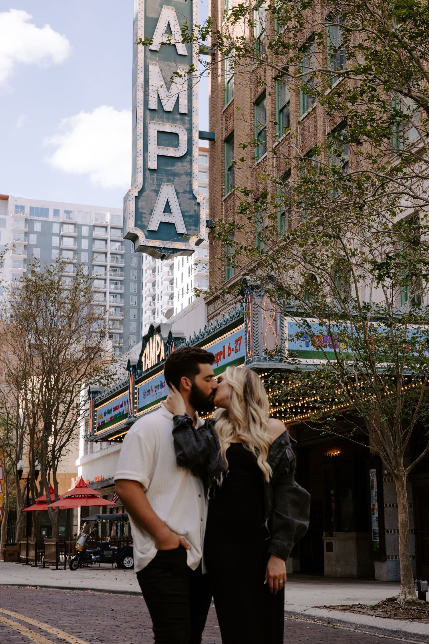 Couple takes romantic photos in front of an urban theater marquee.