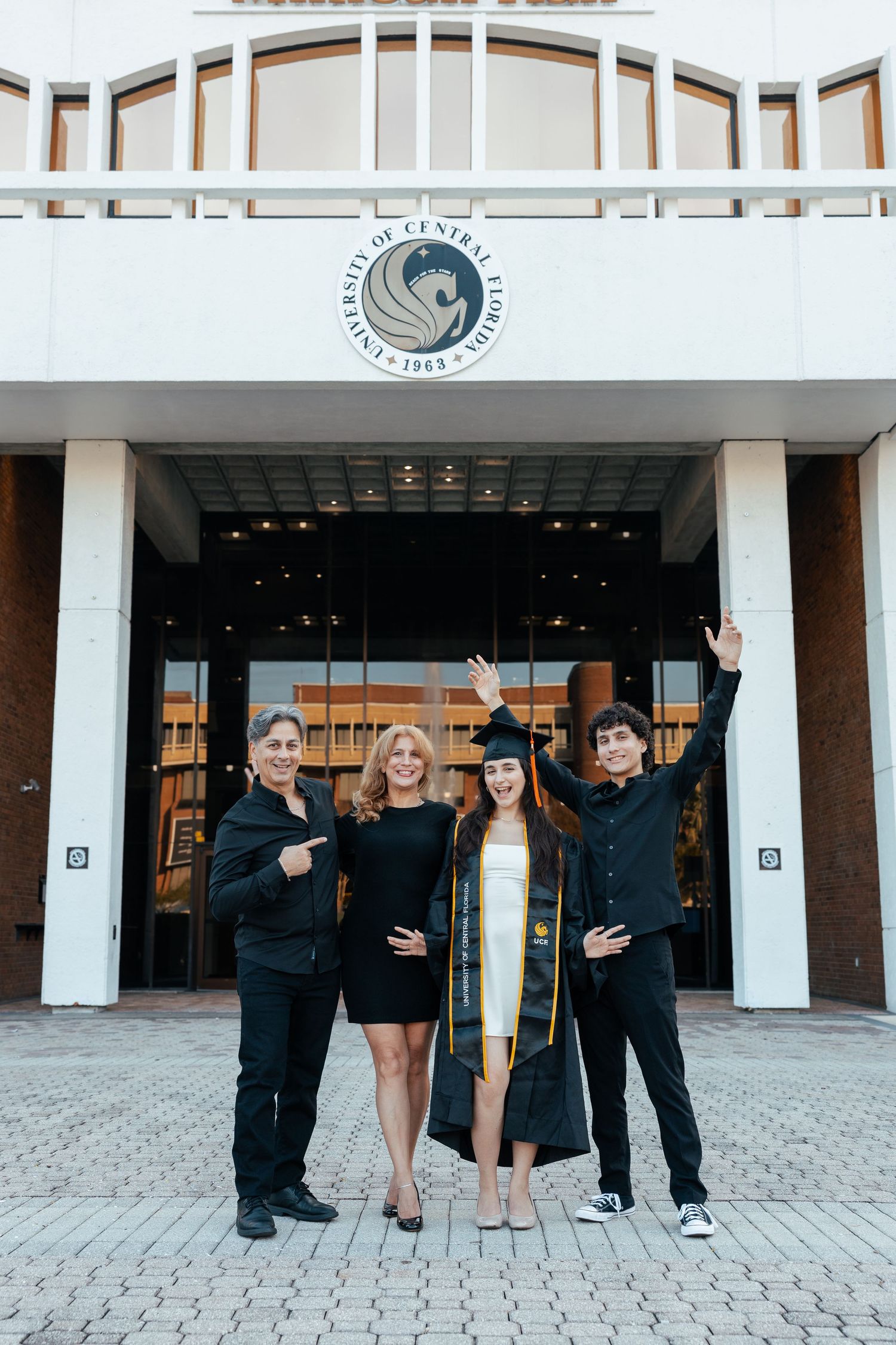 A group poses together in front of a modern building entrance with white columns and glass doors.