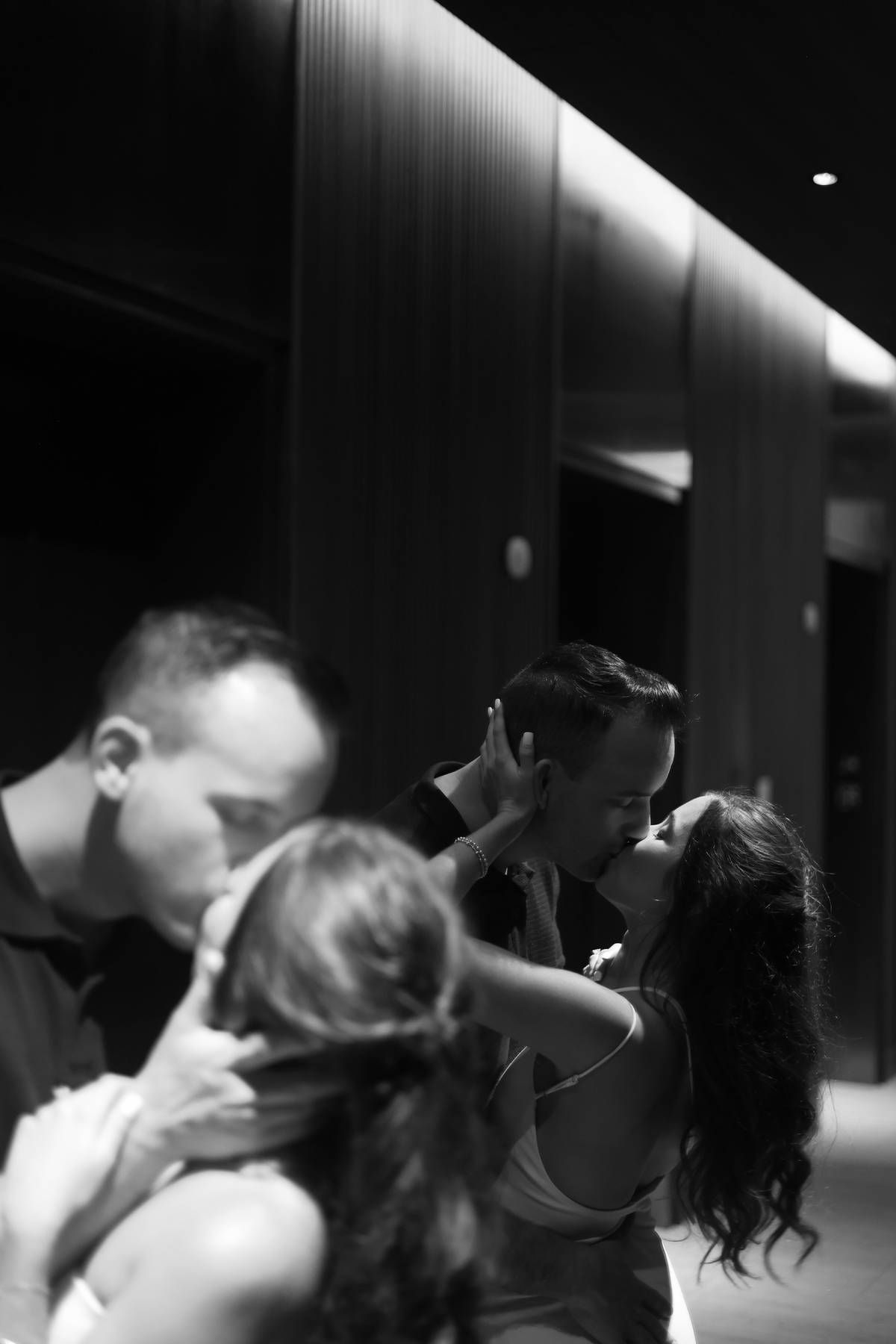 Dramatic black and white sequence of couple's romantic moment in dimly lit hallway.