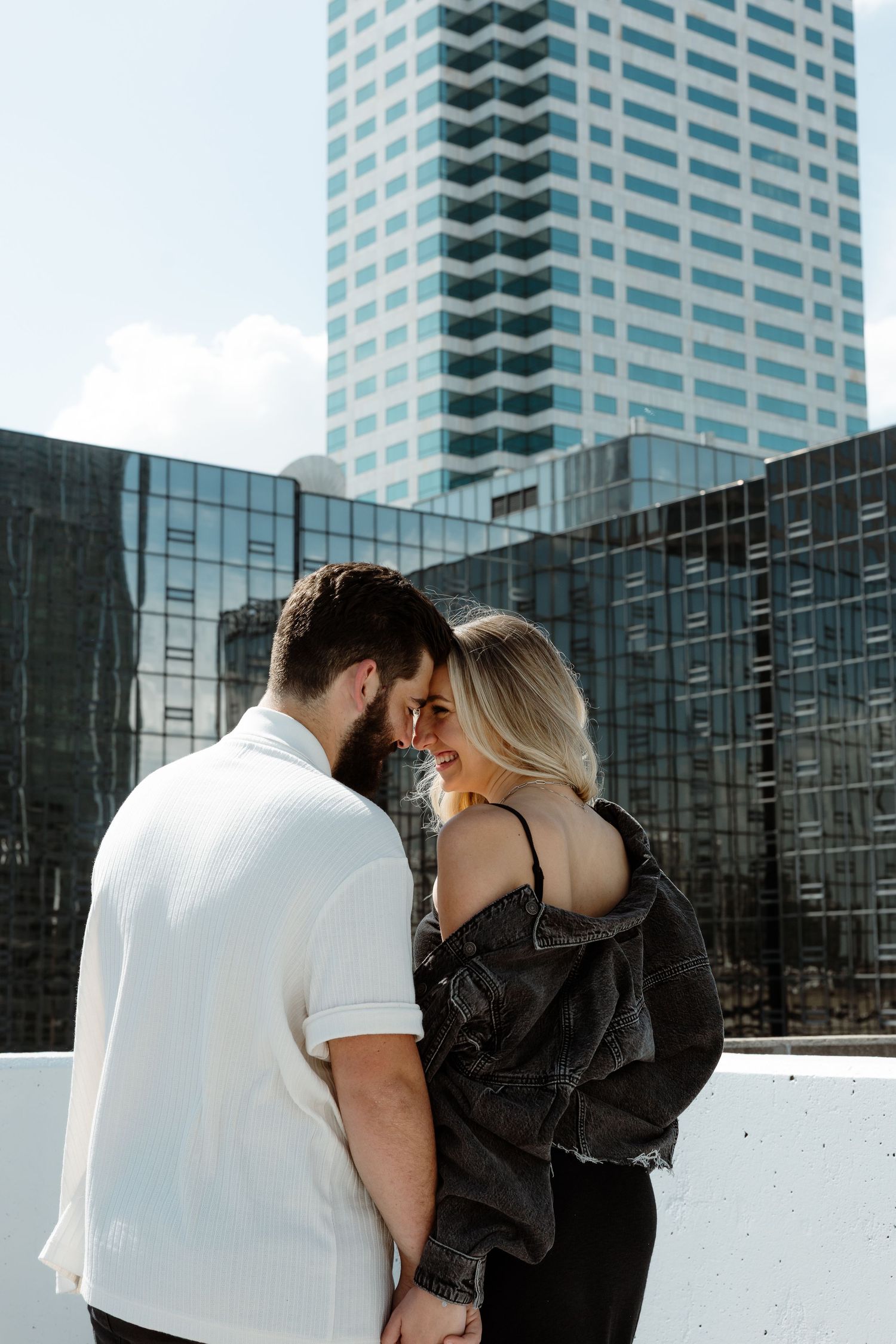 Intimate moment captured on rooftop with modern skyscraper backdrop.