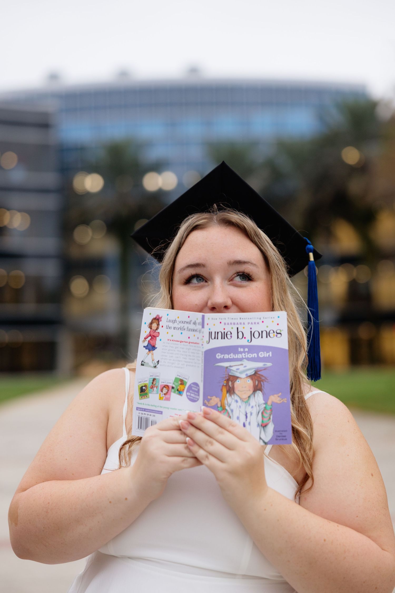 A graduation photo series showing someone playfully hiding behind a Judith D. Hoover book in multiple poses.