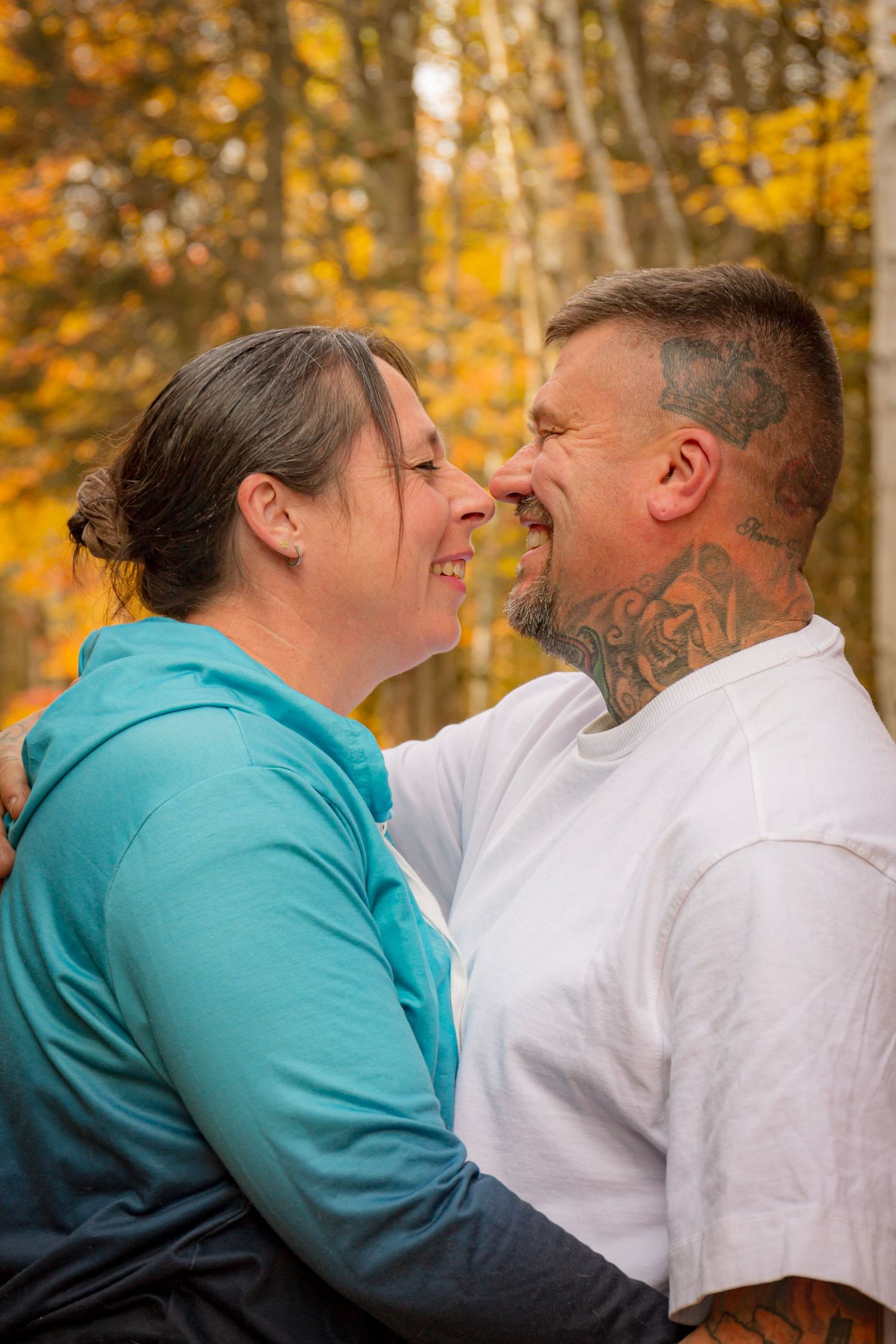 couple snuggling in fall forest setting