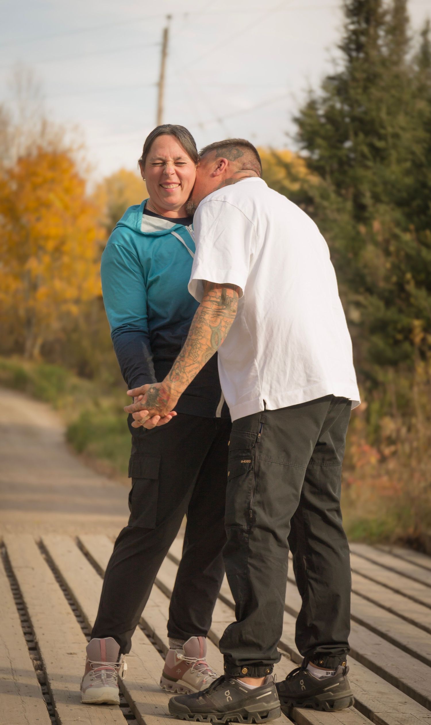woman and a man slow dancing on a foot bridge during the fall season