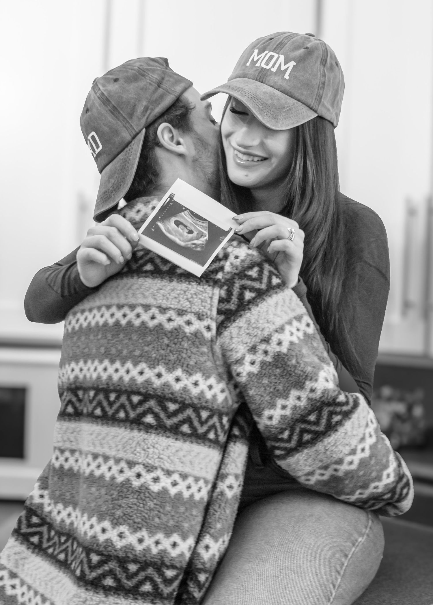 man kissing womans ear and woman holding ultrasound photo