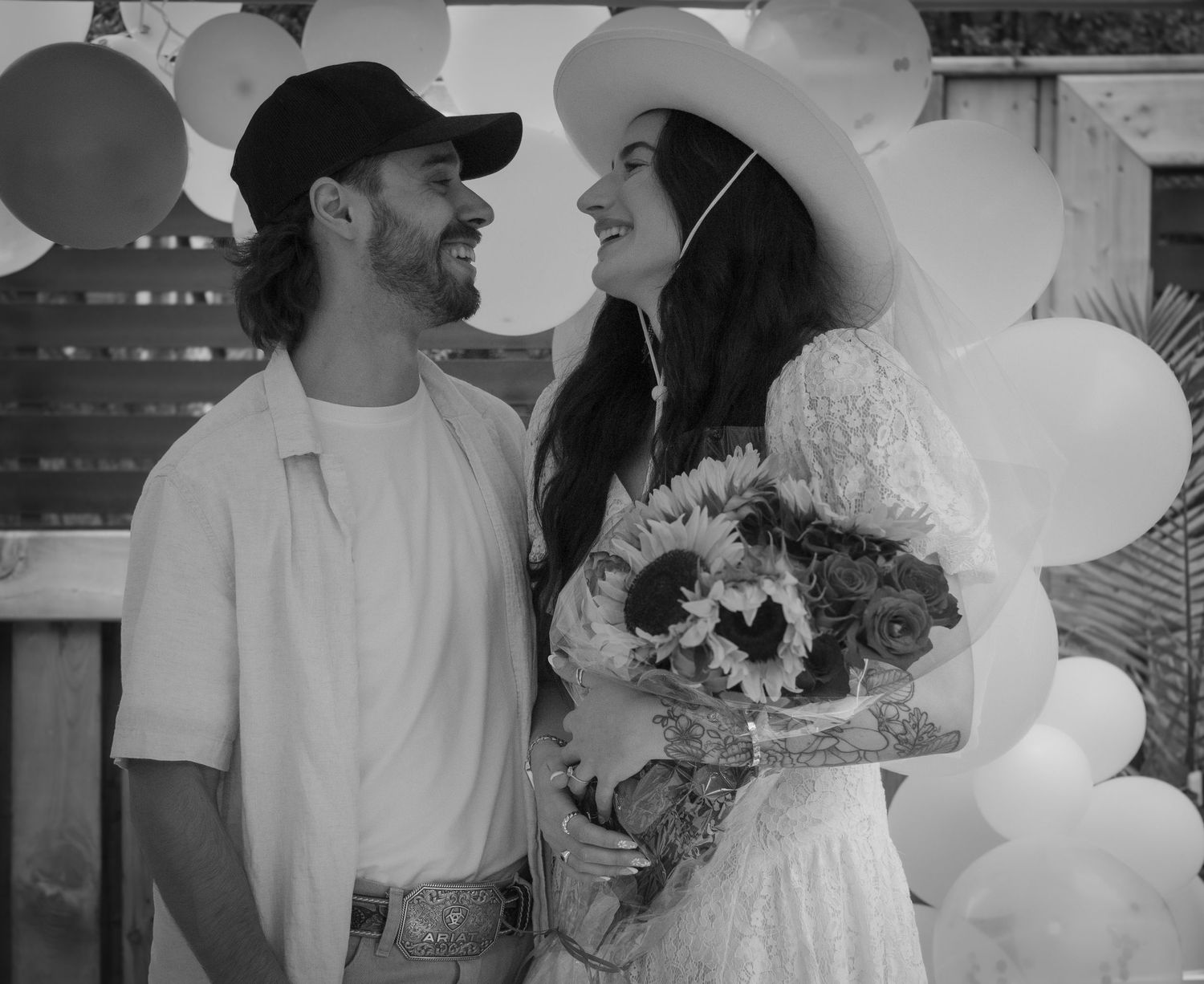 couple looking at eachother. woman is holding a bouquet of flowers