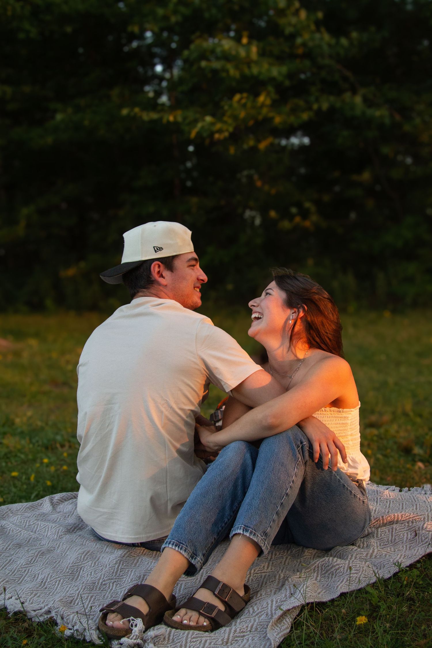 couple sitting on a balnket at beach during sunset