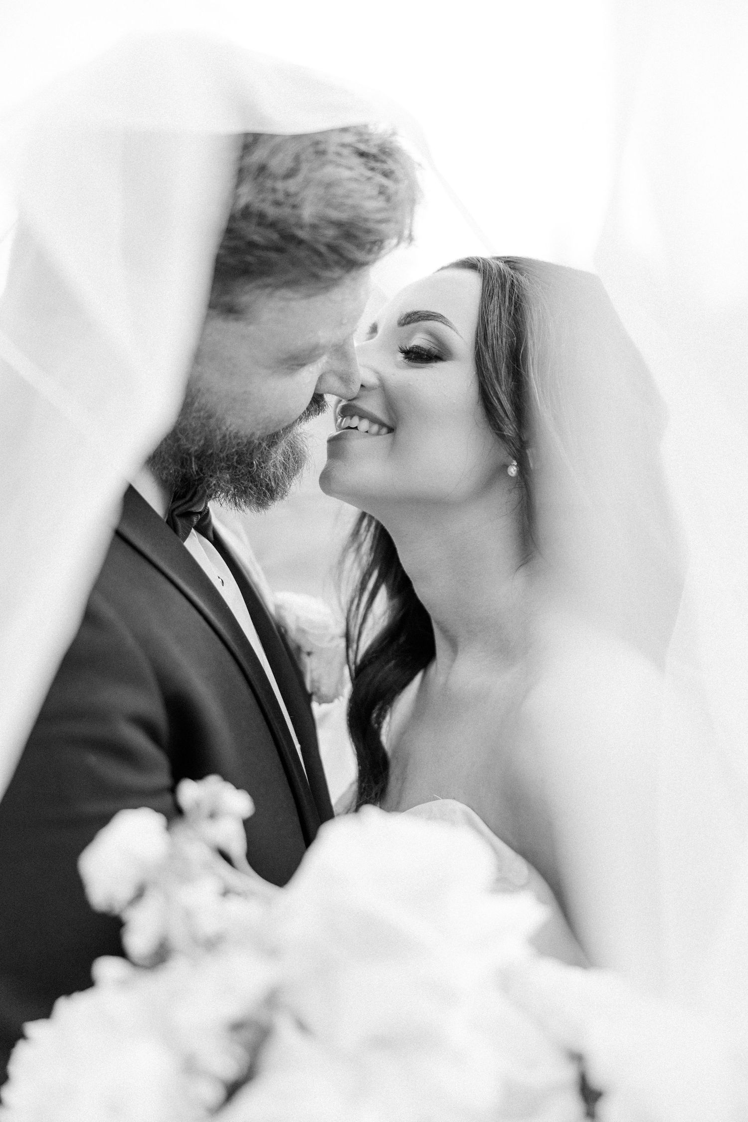 Black and white romantic wedding portraits showing tender moments through a veil.