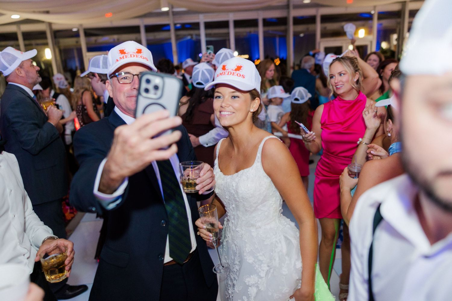 Wedding celebration with guests taking selfies and enjoying drinks at a reception.