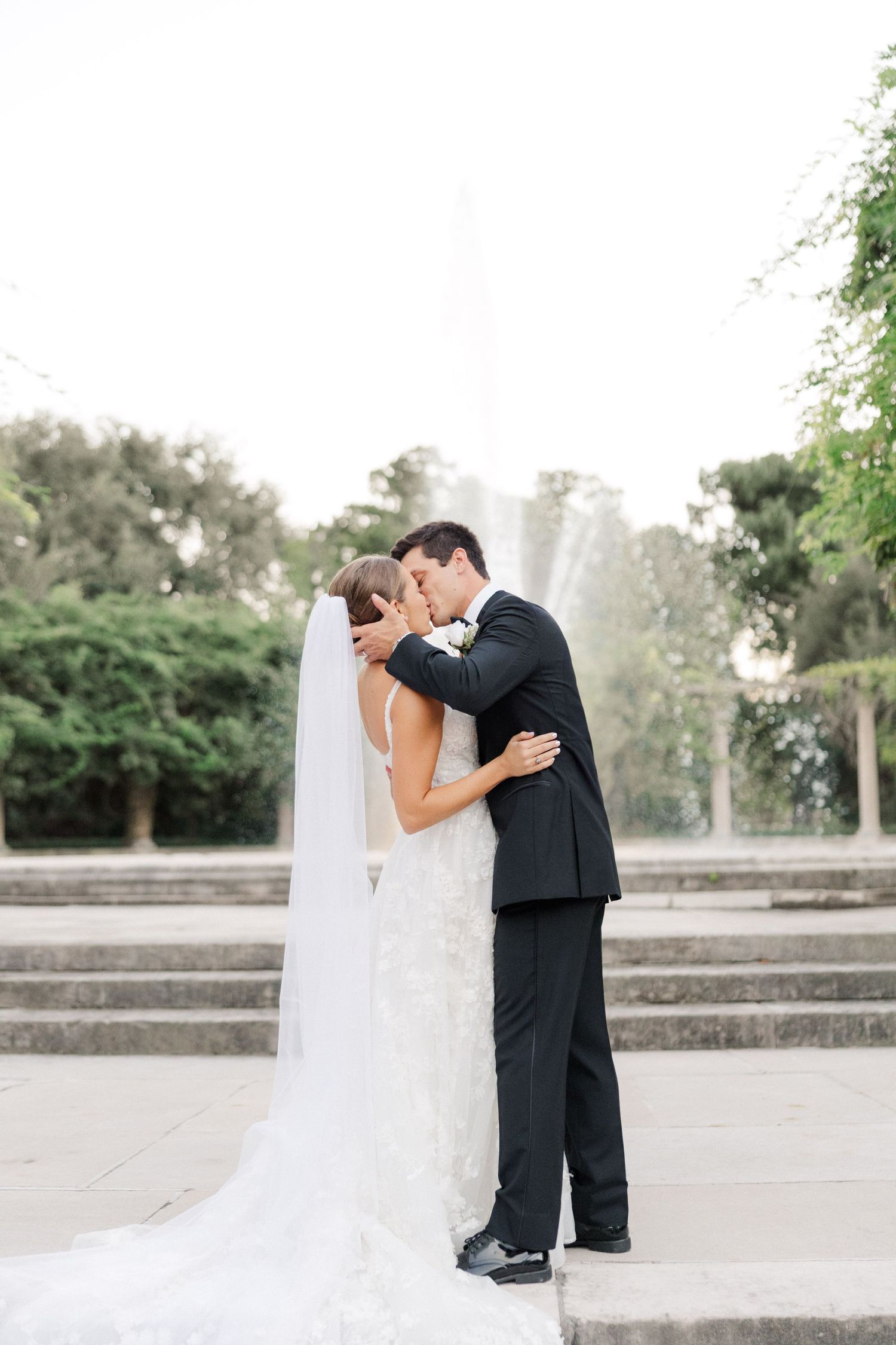 A romantic wedding moment captured on stone steps with greenery in the background.