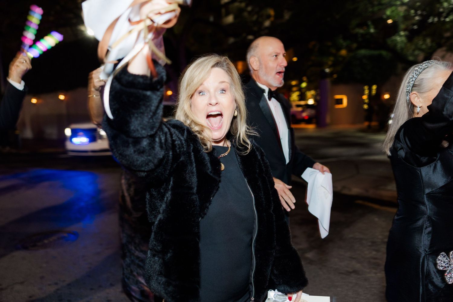 Guest celebrating at nighttime wedding event with raised arms.