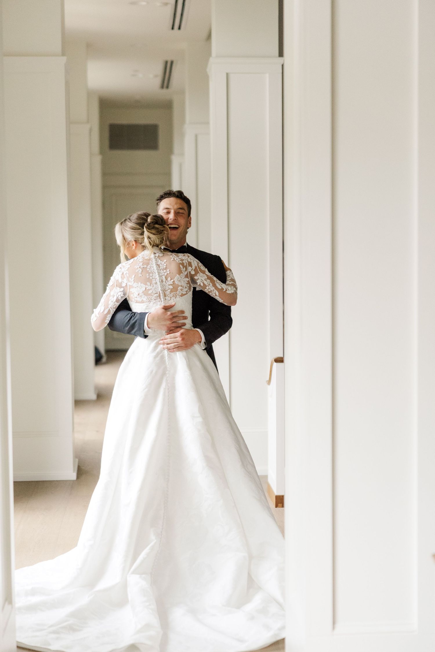 A romantic first look between newlyweds in a bright hallway with white columns.