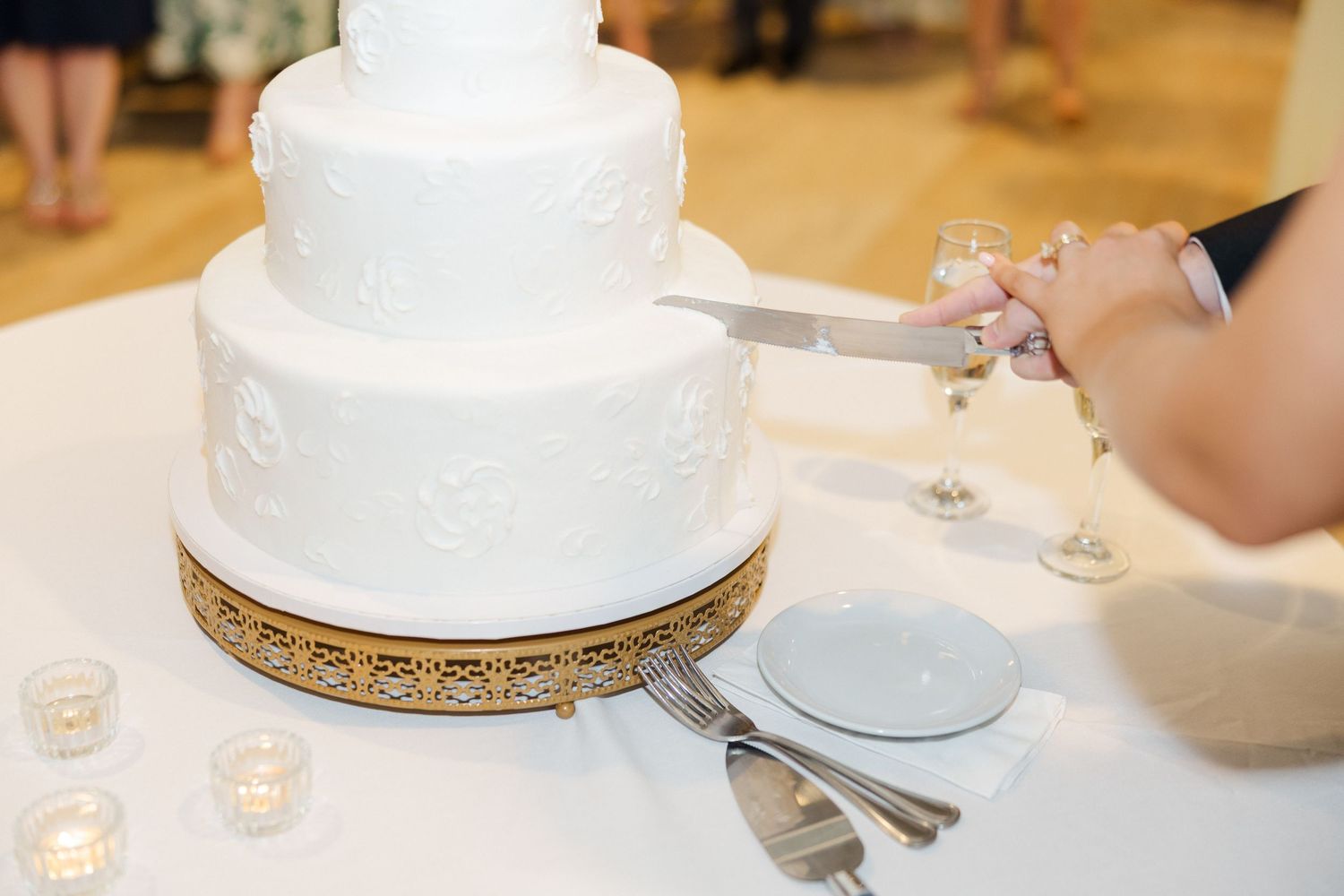 Elegant white wedding cake with gold trim detail on classic white stand.