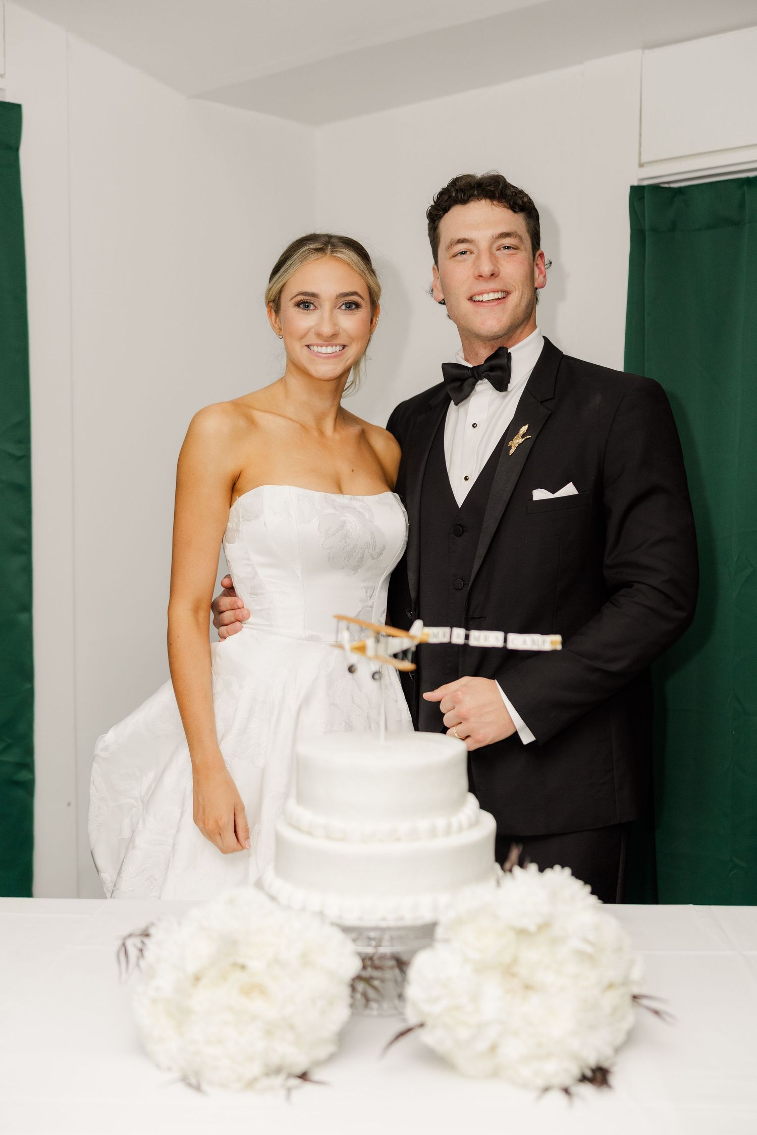 Bride and groom cut their elegant white wedding cake together at reception.